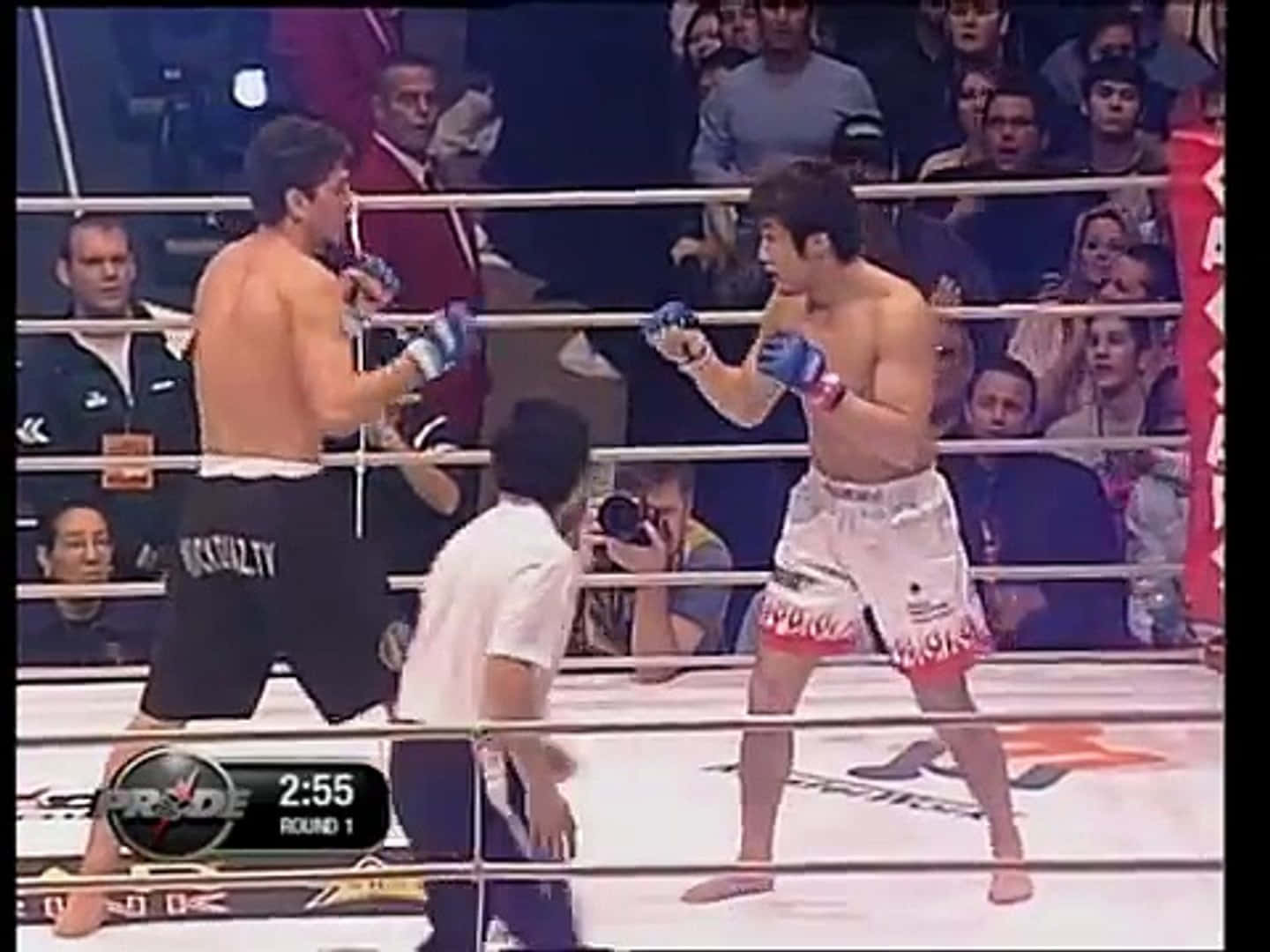 UFC 桌布 壁紙 — 兩位拳手在拳擊擂台上對峙，進行一場職業MMA比賽，裁判和觀眾專注地觀看。