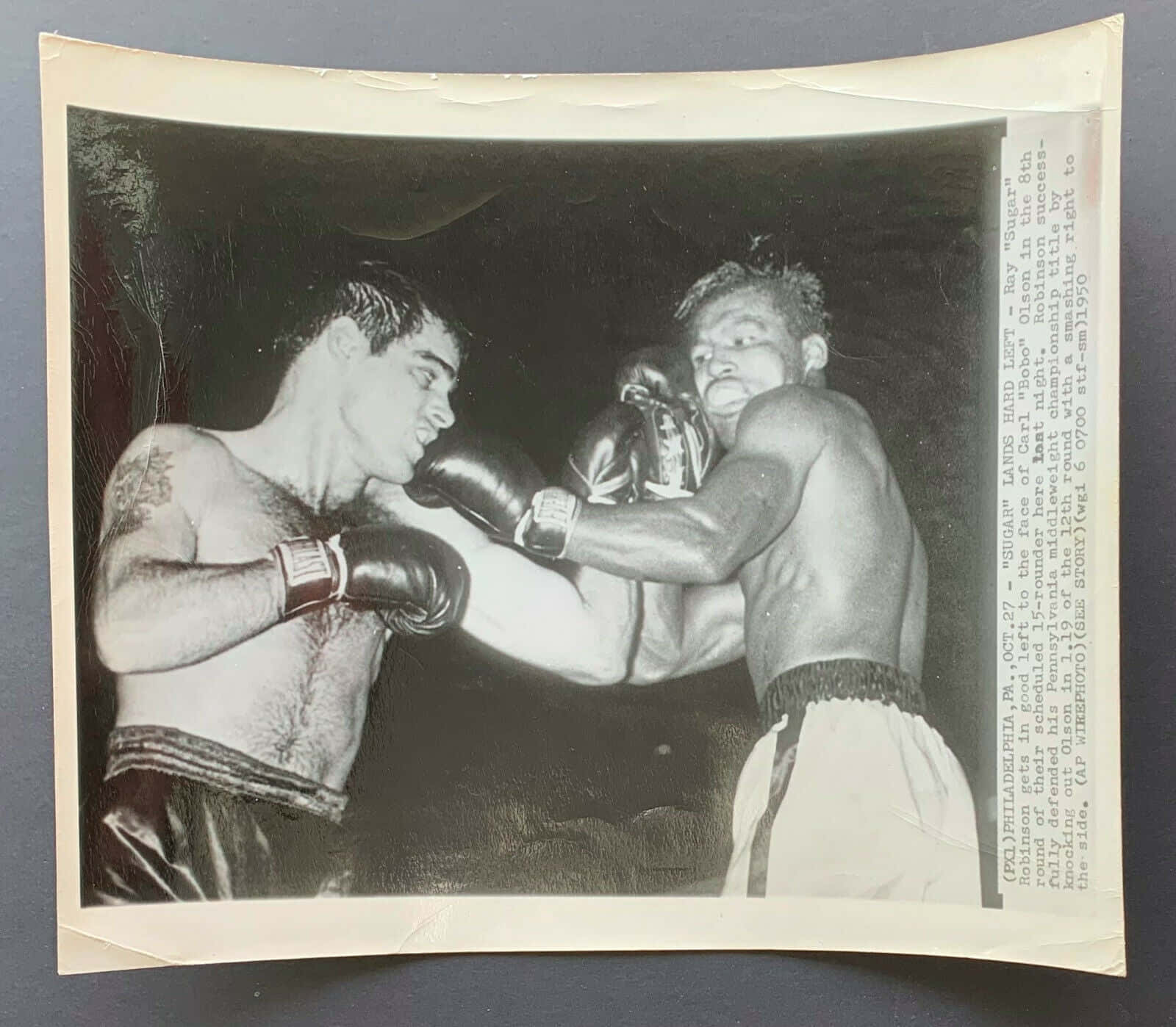 Boxing 桌布 壁紙 — 兩位拳擊手在昏暗場館燈光下，於一張粗糙的黑白照片中激烈碰撞，捕捉到比賽中一記強力拳擊的瞬間。