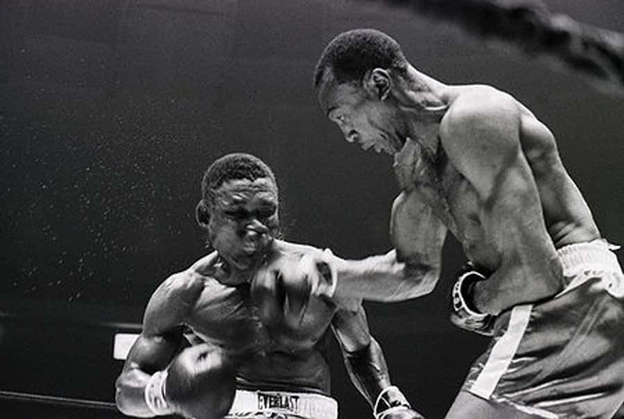 boxer 桌布 壁紙 — 兩位拳擊手在粗糙的黑白擂台上激烈交鋒，汗水飛濺，其中一人擊出強力一拳。