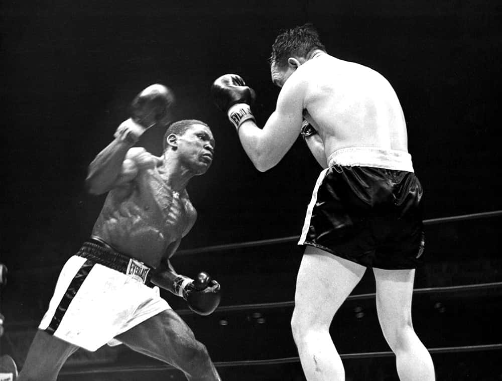 boxer 桌布 壁紙 — 兩位拳擊手在黑白戲劇性的拳擊場場景中碰撞，動態模糊捕捉了激烈的動作。