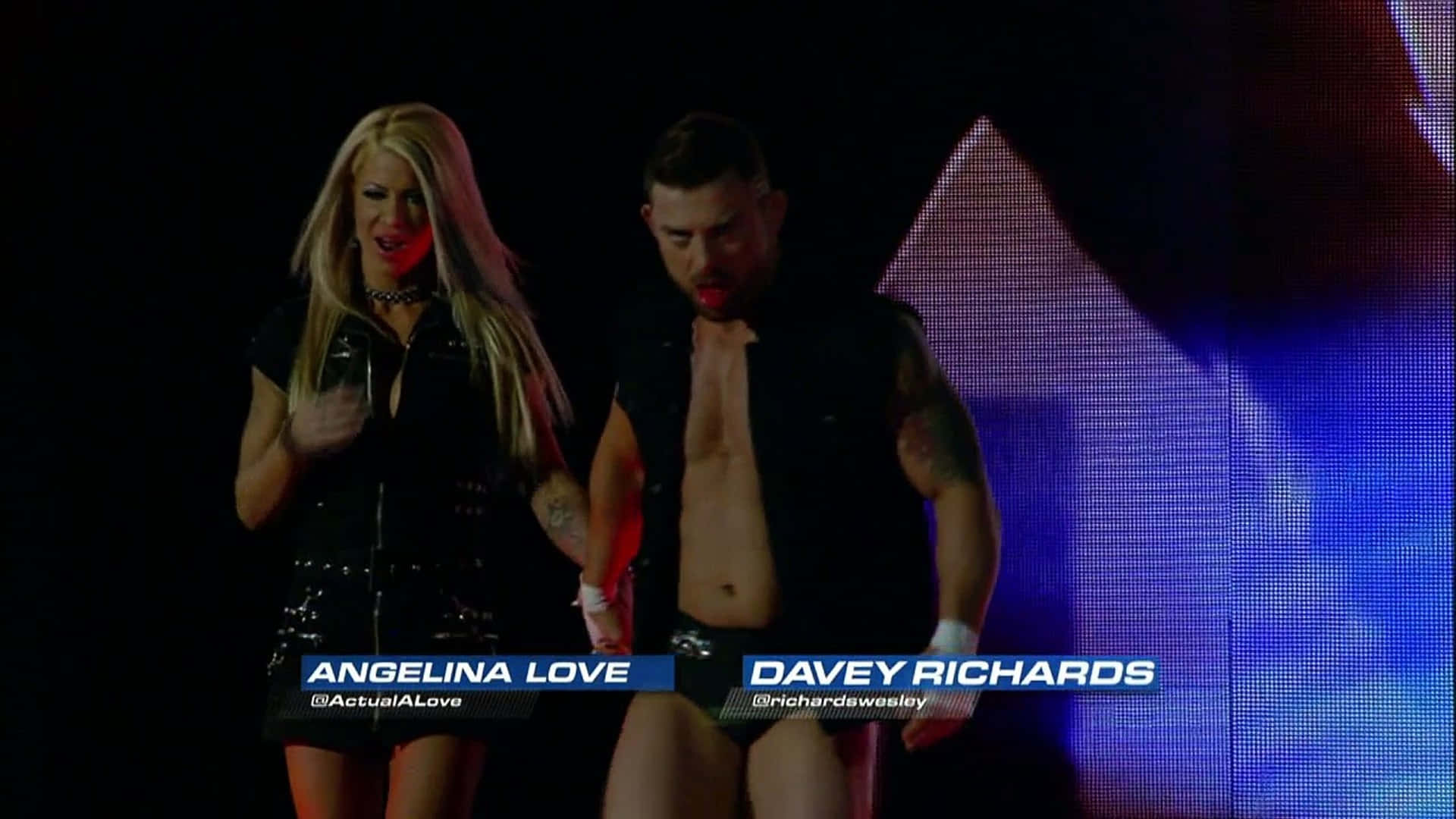 WWE 桌布 壁紙 — 兩位摔角手 Angelina Love 和 Davey Richards 在明亮的舞台燈光下手牽手走過，背景是像素化的。
