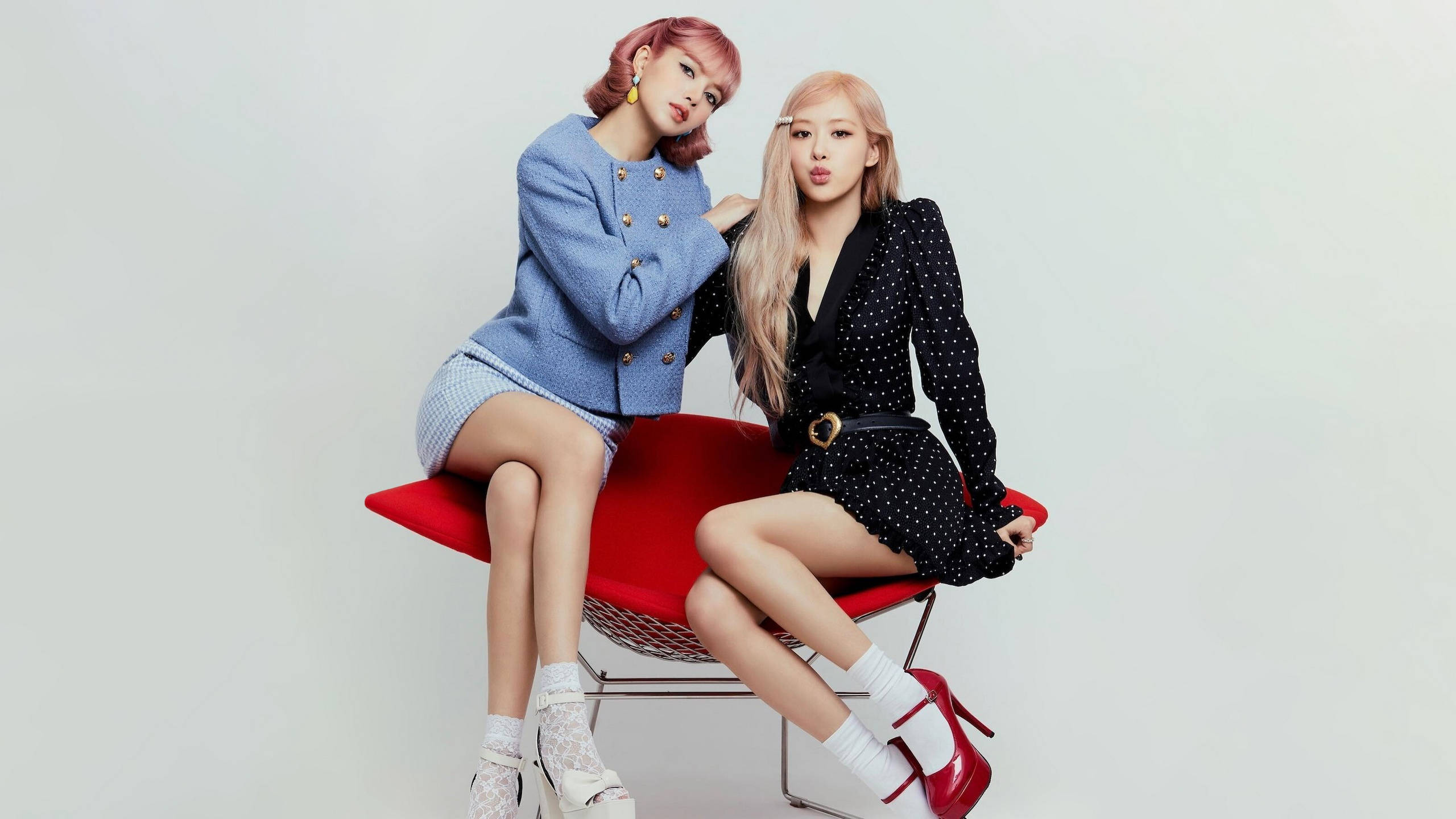 BLACKPINK 桌布 壁紙 — 兩位時尚女性自信地坐在一張大膽的紅色椅子上，背景是簡約的白色。