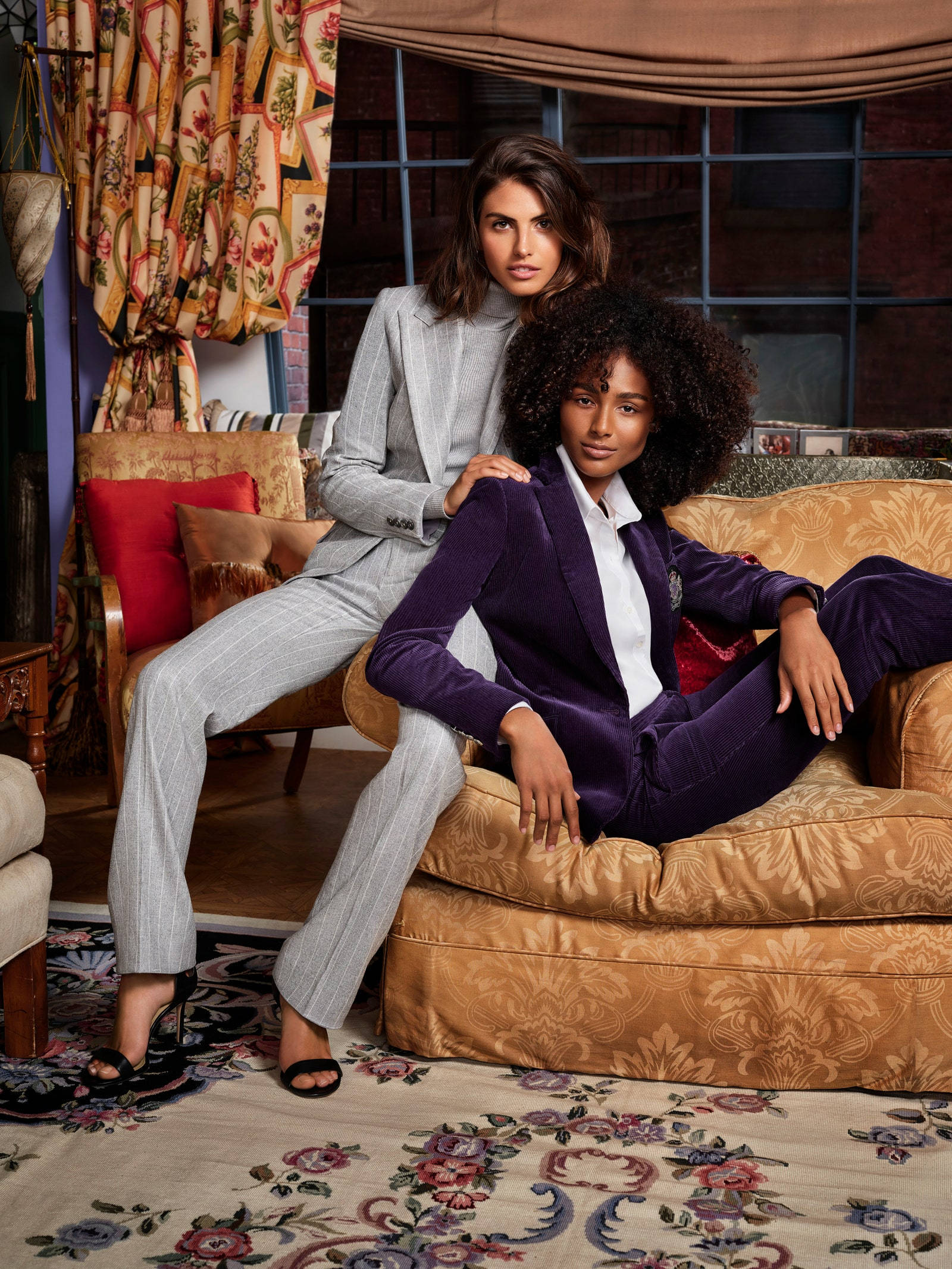 ralph lauren 桌布 壁紙 — 兩位時尚女性自信地擺姿勢，坐在裝飾華麗的復古客廳中的華麗家具上。