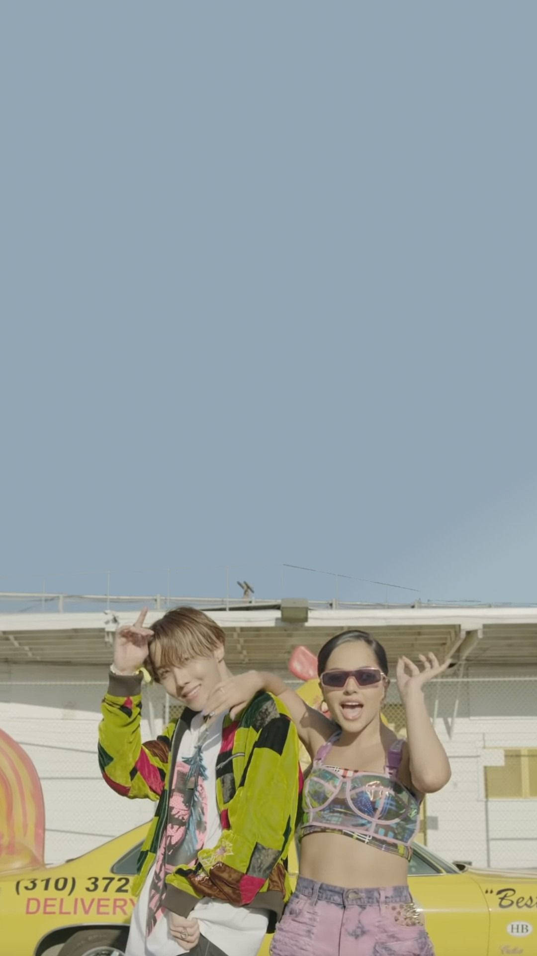j-hope 桌布 壁紙 — 兩位時尚年輕人在晴朗藍天下，俏皮地在一輛黃色送貨車旁擺姿勢。