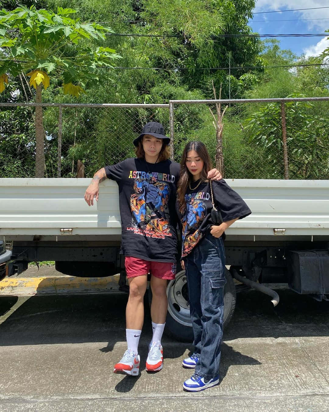 Matching Couple Profile 桌布 壁紙 — 兩位時尚年輕人自信地站在白色卡車旁，背後是晴朗的天空和茂密的綠色樹葉。