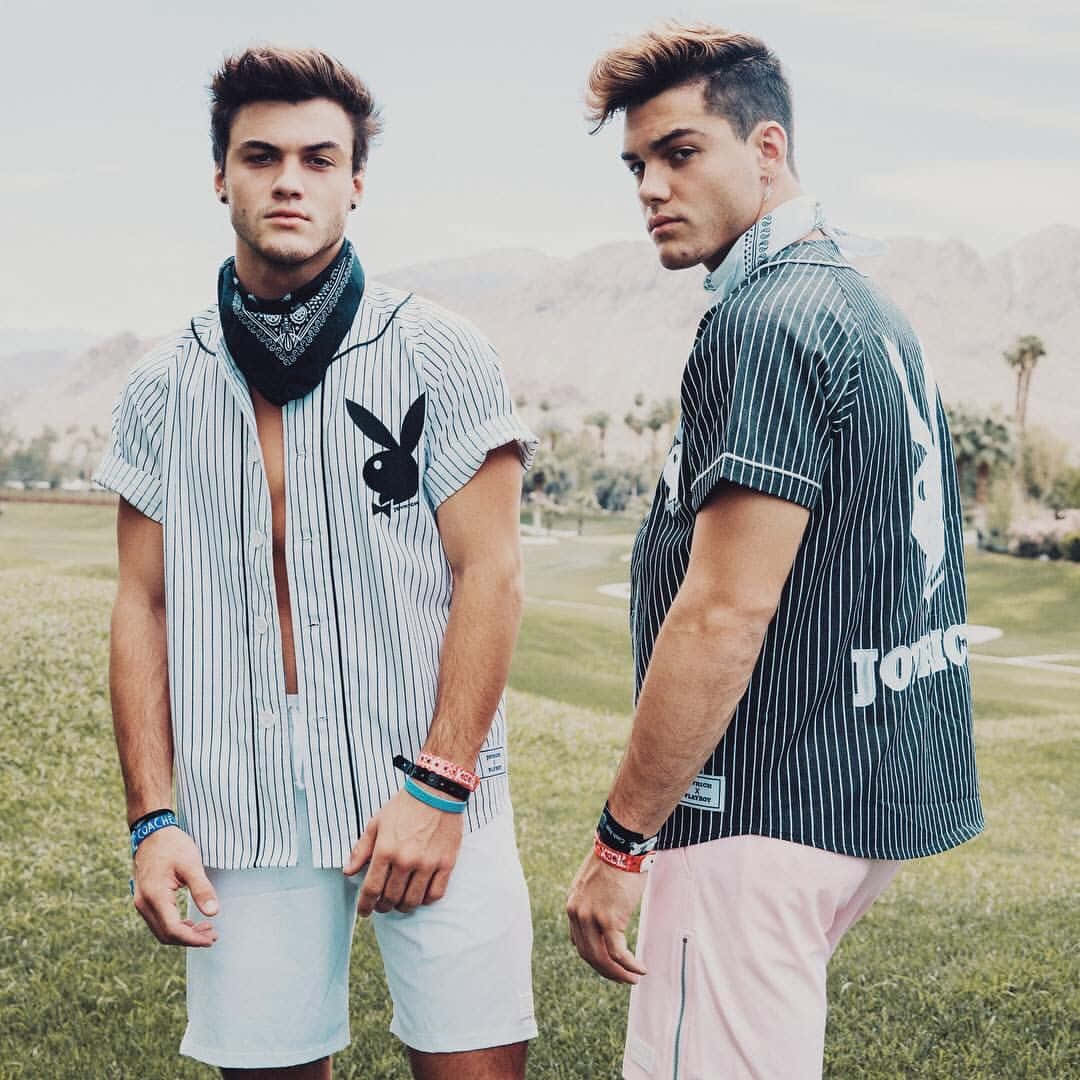 twins 桌布 壁紙 — 兩位時尚年輕男士身穿條紋Playboy襯衫，自信地站在草地上，背景是山脈。