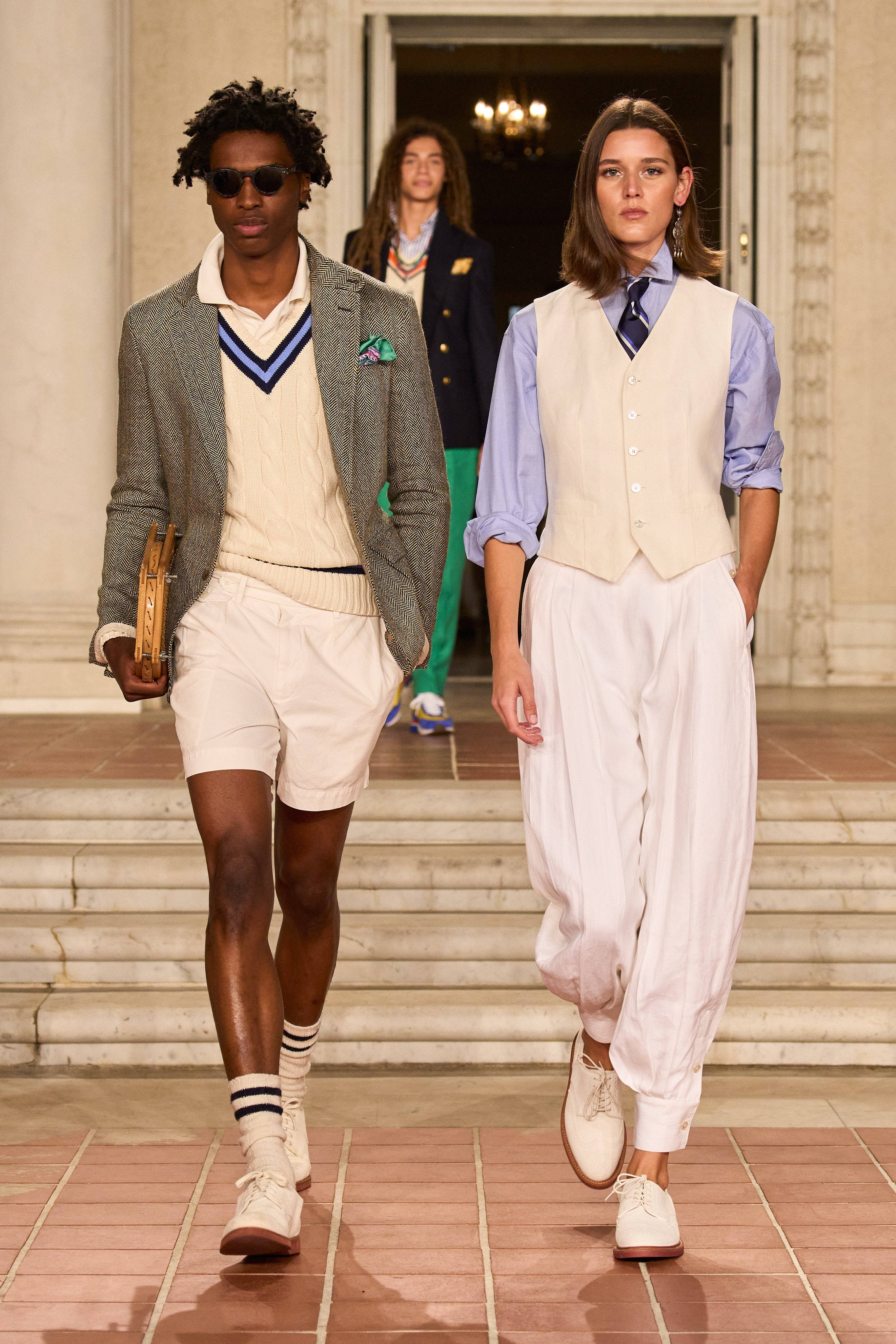 Preppy 桌布 壁紙 — 兩位模特兒在溫暖的室內燈光下，穿著量身定制的預科生風格服裝，自信地走下宏偉的瓷磚樓梯。