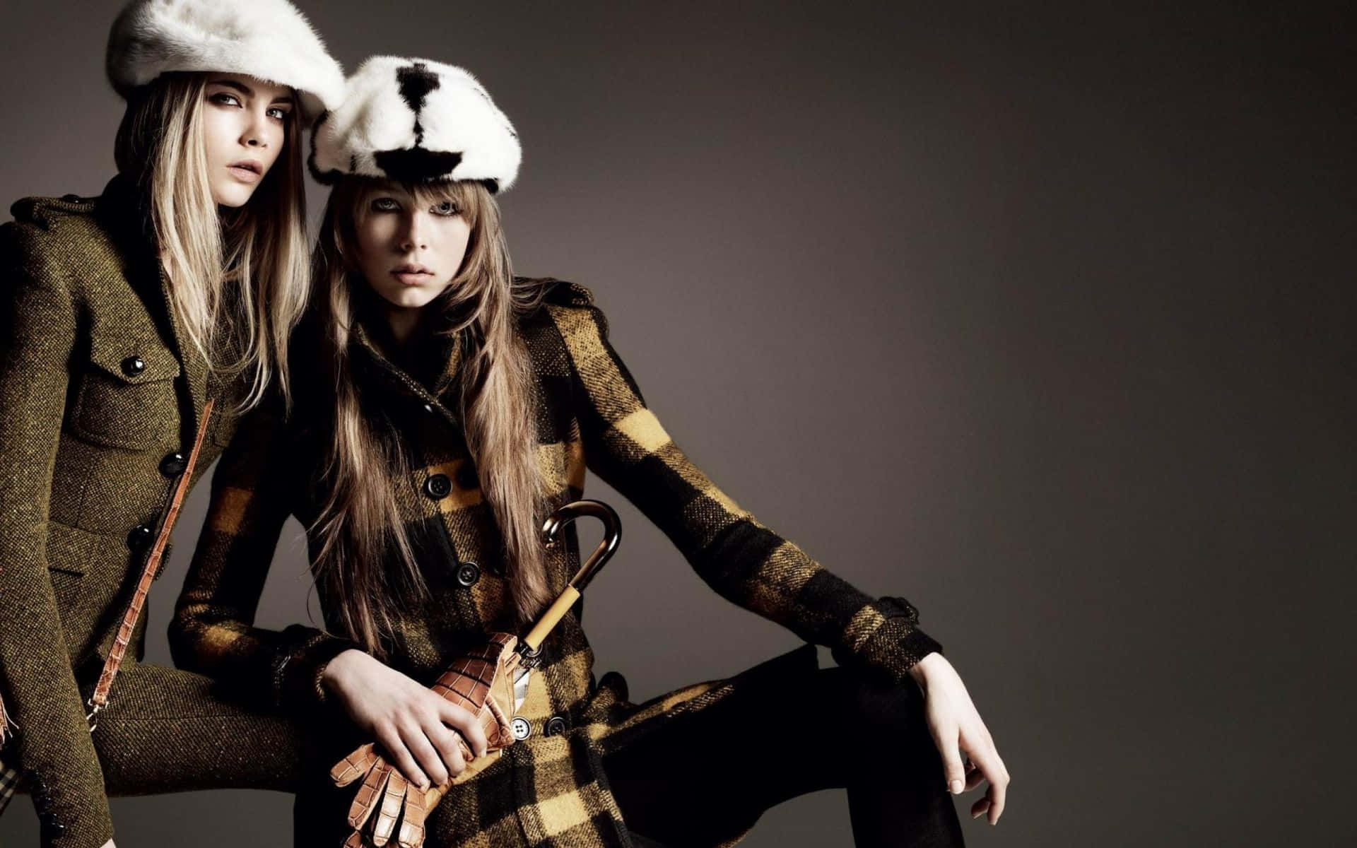 Winter Fashion 桌布 壁紙 — 兩位模特兒穿著格紋外套和毛帽，在柔和的灰色背景前擺出嚴肅的表情。