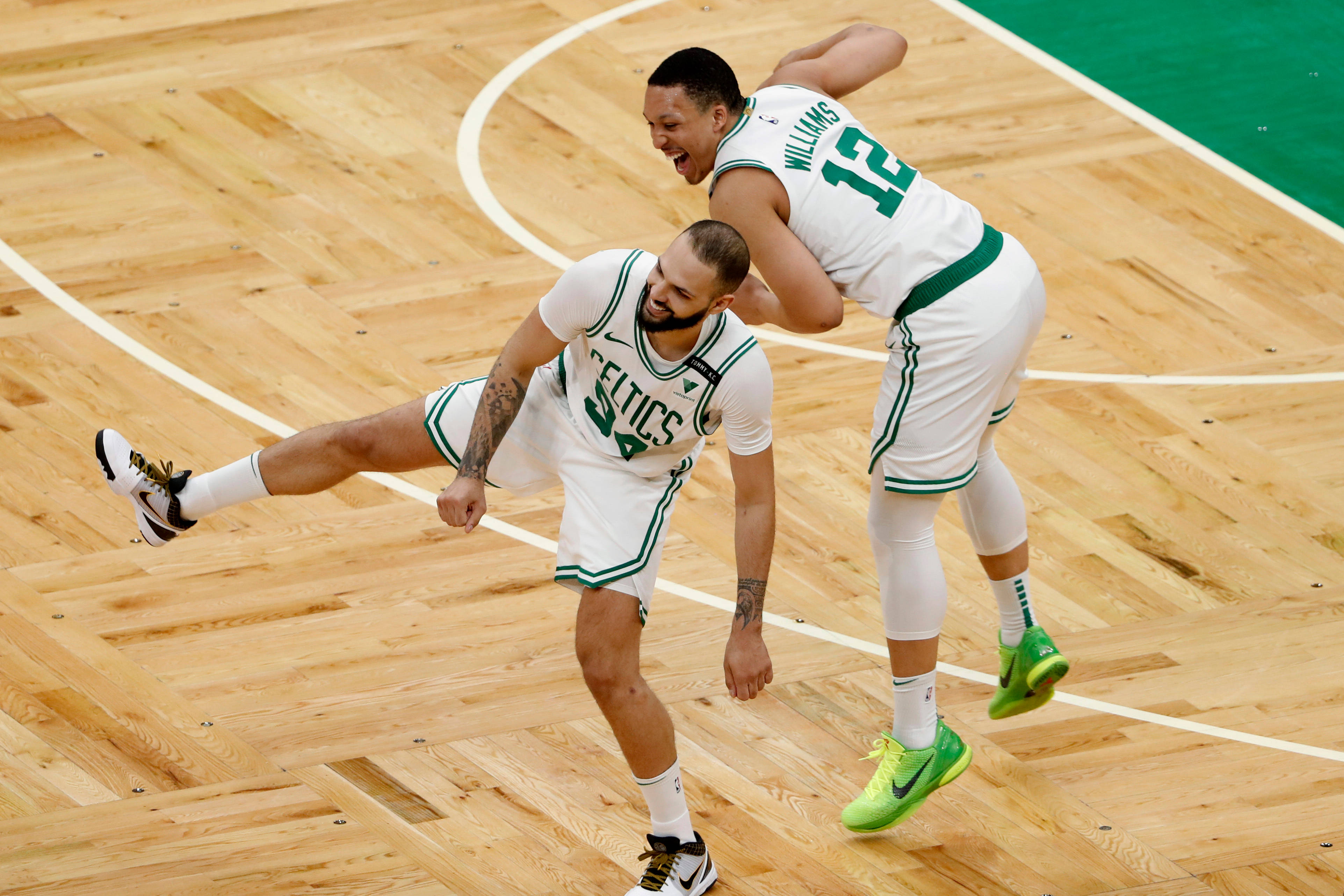 NBA 桌布 壁紙 — 兩位波士頓塞爾提克籃球運動員在木地板上興高采烈地慶祝，一人跳躍歡呼，另一人踢腿。