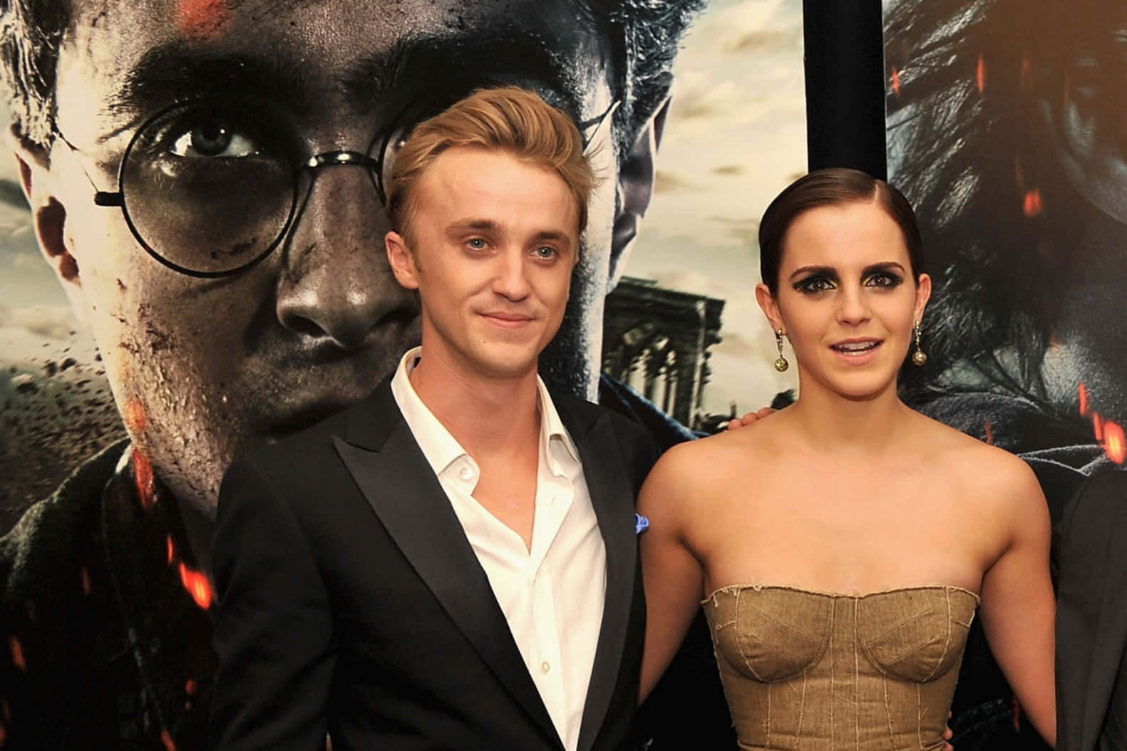 Emma Watson 桌布 壁紙 — 兩位演員在一張有火焰火花和城堡背景的哈利波特電影海報前擺姿勢。