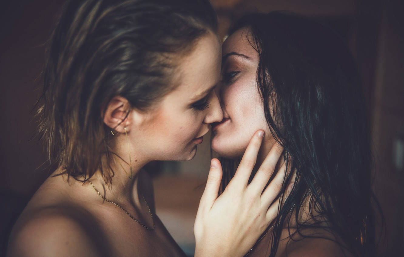 女同志 桌布 壁紙 — 兩位濕髮女性在光線昏暗、帶有柔和溫暖照明的房間裡親密接吻。