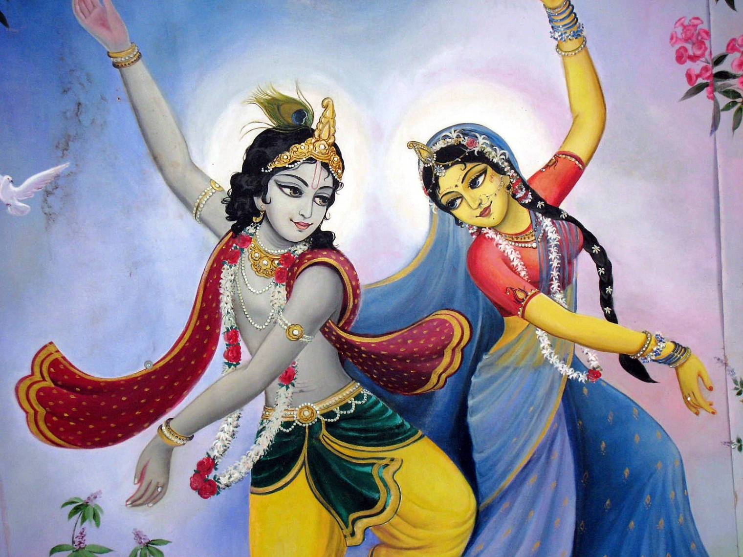Hindu God 桌布 壁紙 — 兩位神聖人物穿著鮮豔的傳統服裝，在柔和的粉彩天空下優雅起舞，附近有一隻白鴿飛翔。