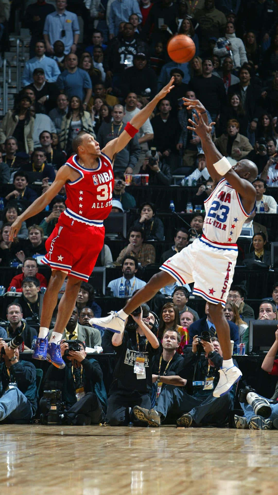 Jordan And Kobe 桌布 壁紙 — 兩位籃球運動員在NBA全明星賽期間於半空中跳起，在擠滿觀眾的場館前爭奪投籃。