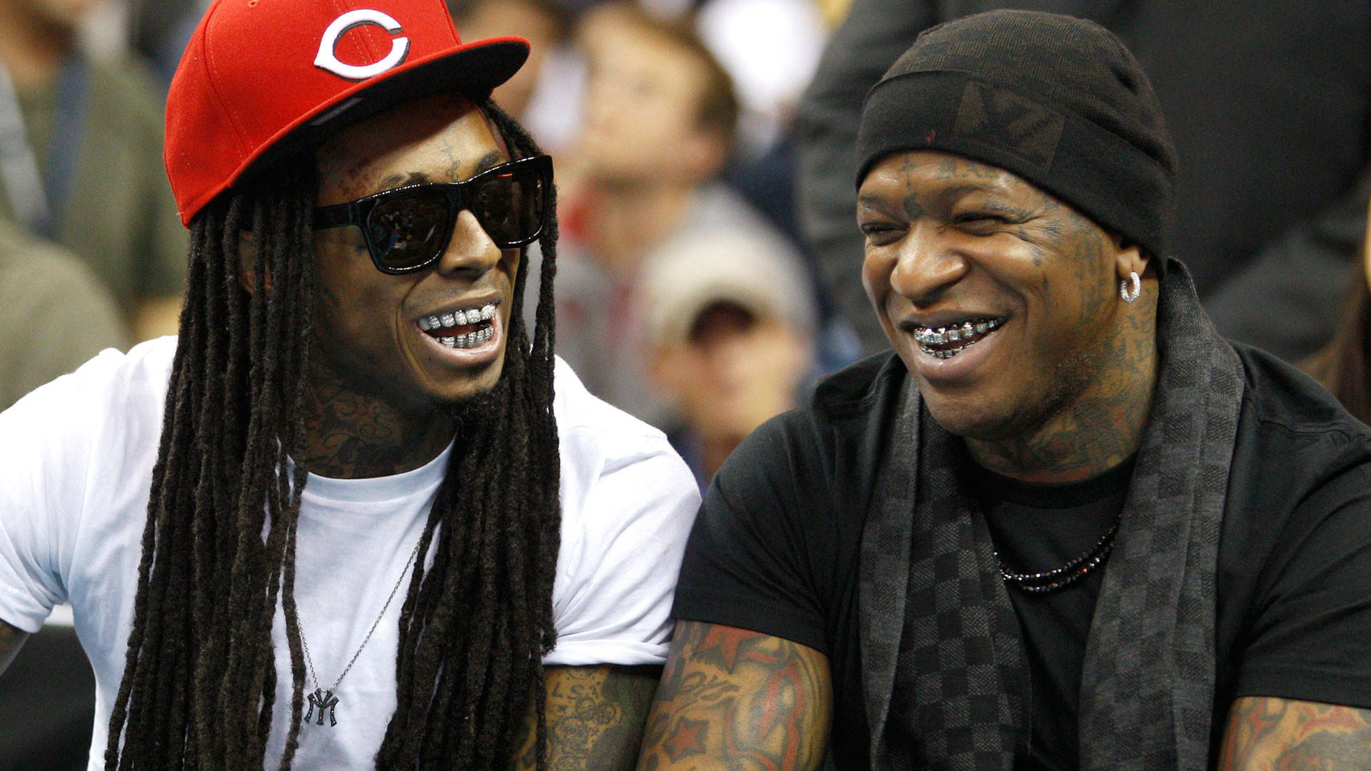 Lil Wayne 桌布 壁紙 — 兩位紋身男子面帶笑容、戴著太陽眼鏡，在擠滿人群的活動中分享歡樂時刻。