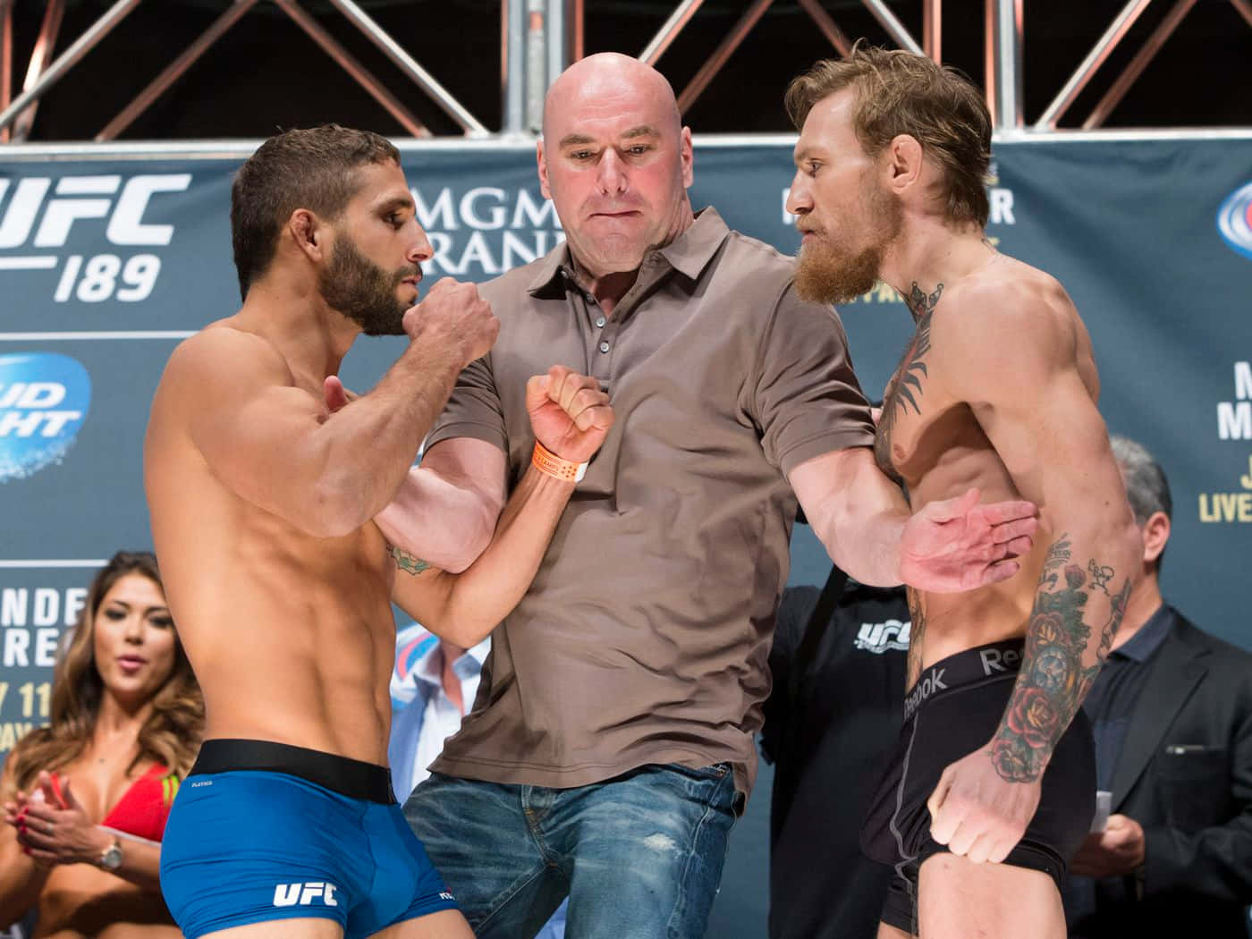 MMA 桌布 壁紙 — 兩位肌肉發達的UFC拳手在明亮的場館燈光下對峙，裁判在重大賽事前將他們的手臂分開。