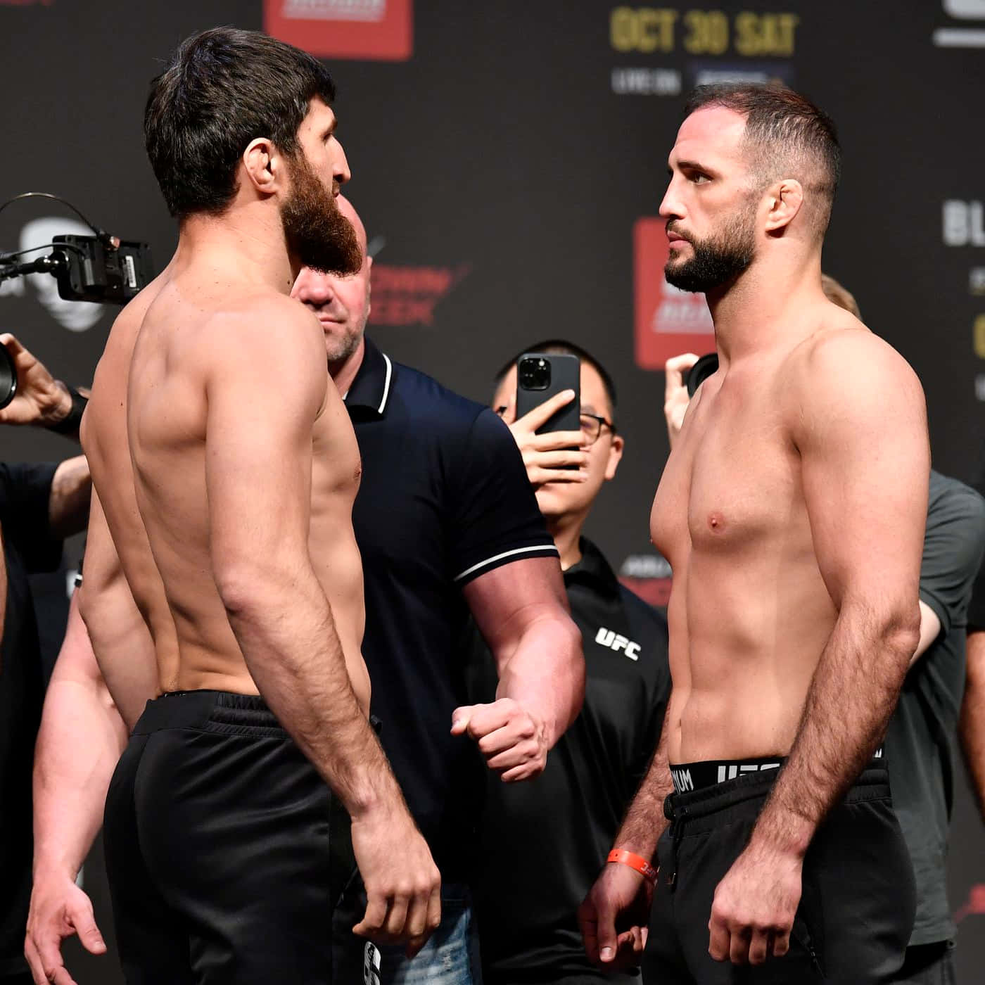 MMA 桌布 壁紙 — 兩位肌肉發達的UFC拳手在稱重儀式上激烈對峙，周圍閃光燈不斷。