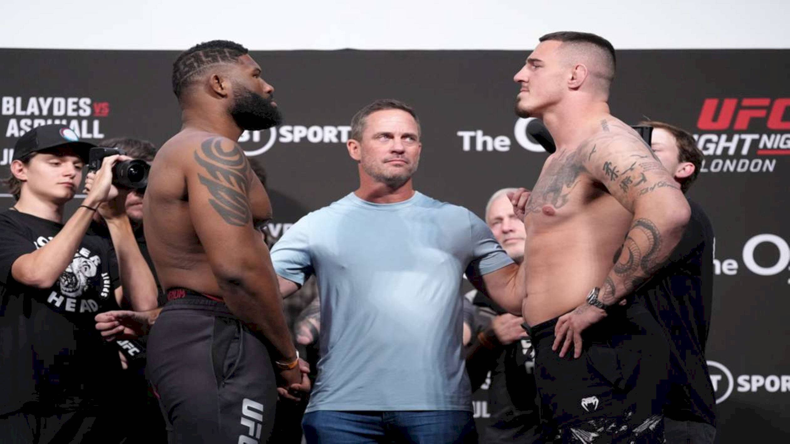 MMA 桌布 壁紙 — 兩位肌肉發達的UFC拳手在稱重時對峙，中間有裁判，攝影師捕捉緊張時刻。