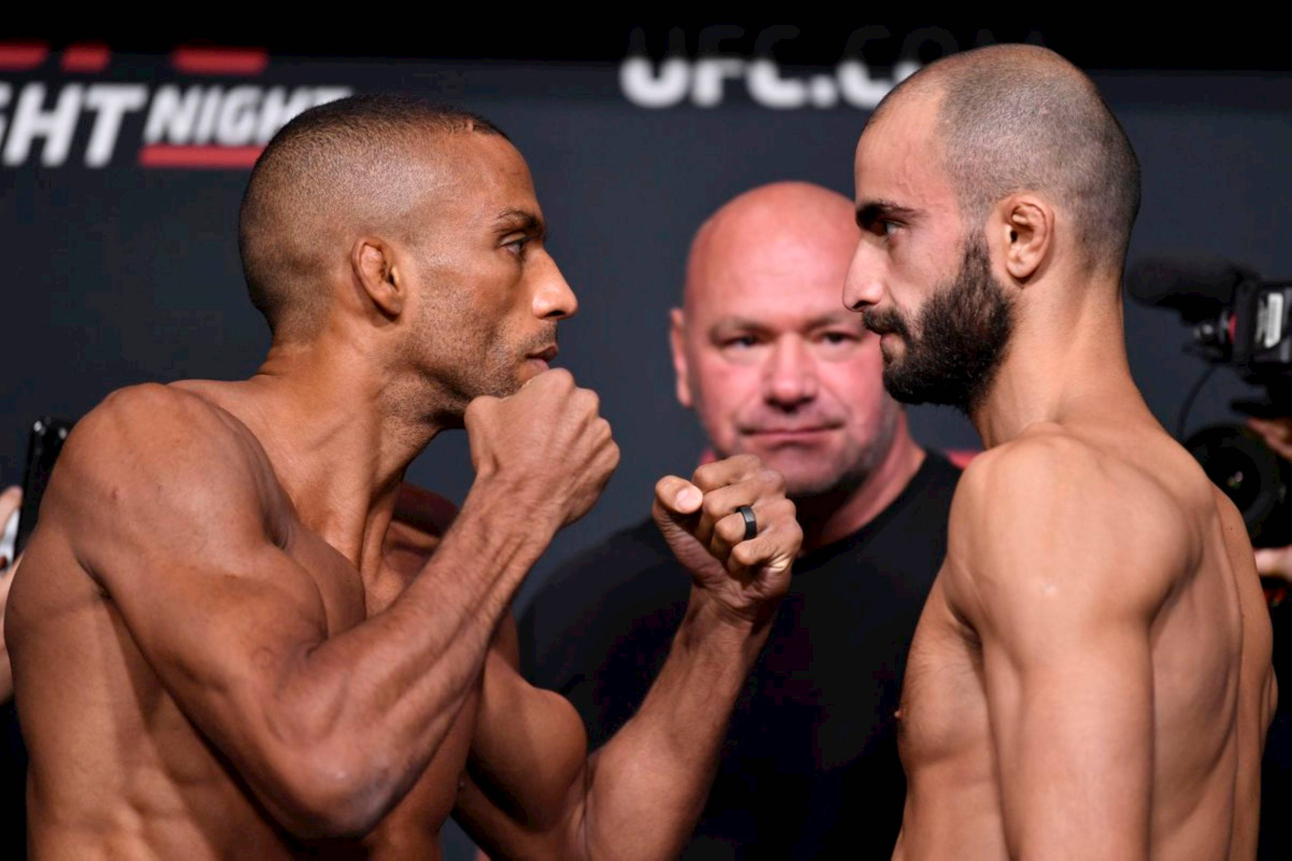 UFC 桌布 壁紙 — 兩位肌肉發達的UFC拳手在緊張的賽前對峙中舉起拳頭。