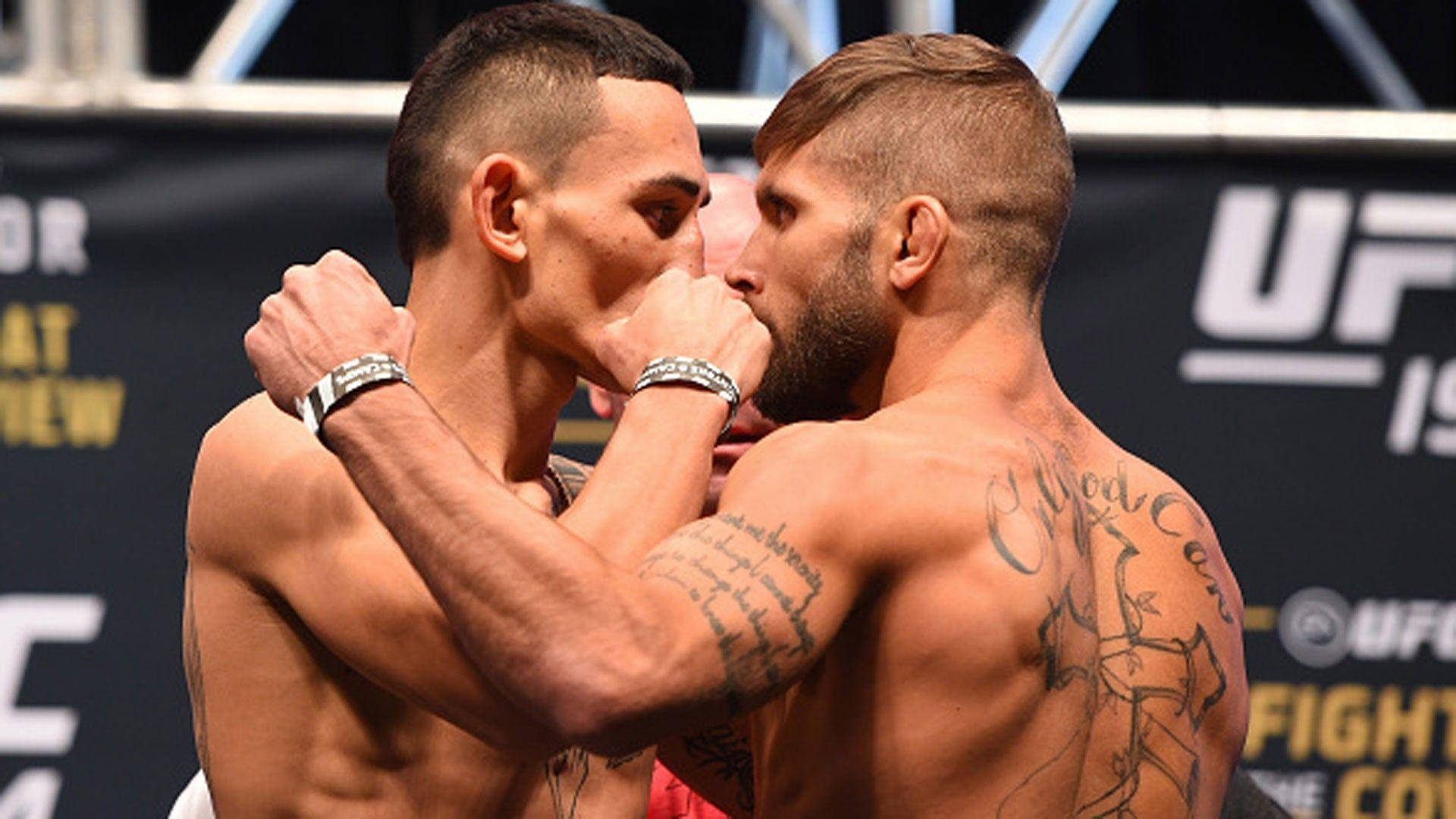 UFC 桌布 壁紙 — 兩位肌肉發達的UFC拳手在緊張的賽前對峙中，紋身手臂鎖定在戰鬥姿勢。