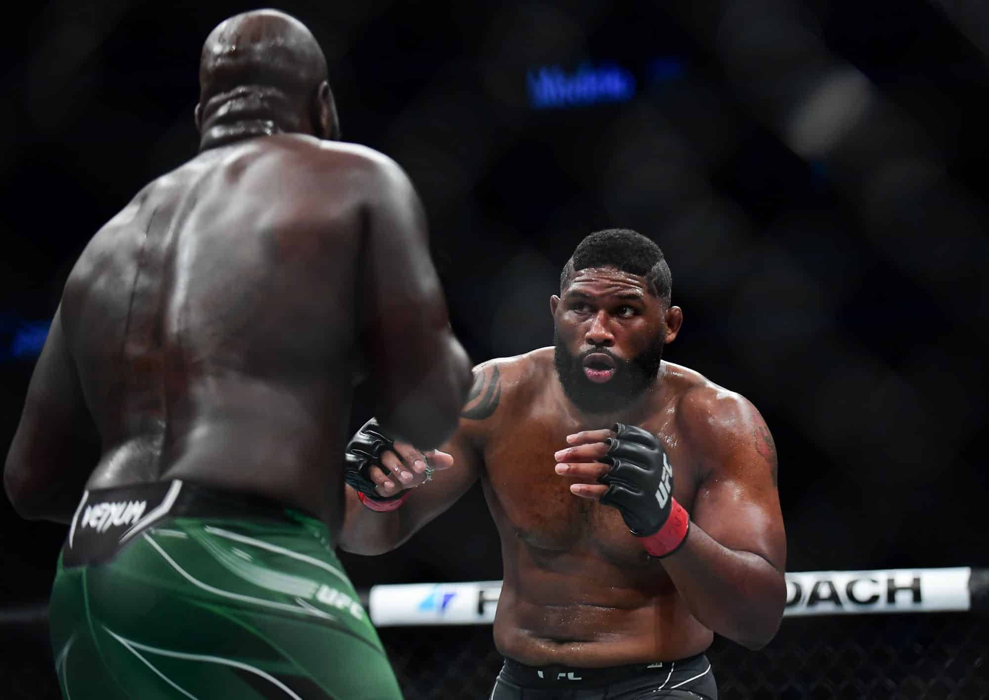 MMA 桌布 壁紙 — 兩位肌肉發達的拳手在明亮的場館燈光下，在UFC八角籠中對峙，神情專注。