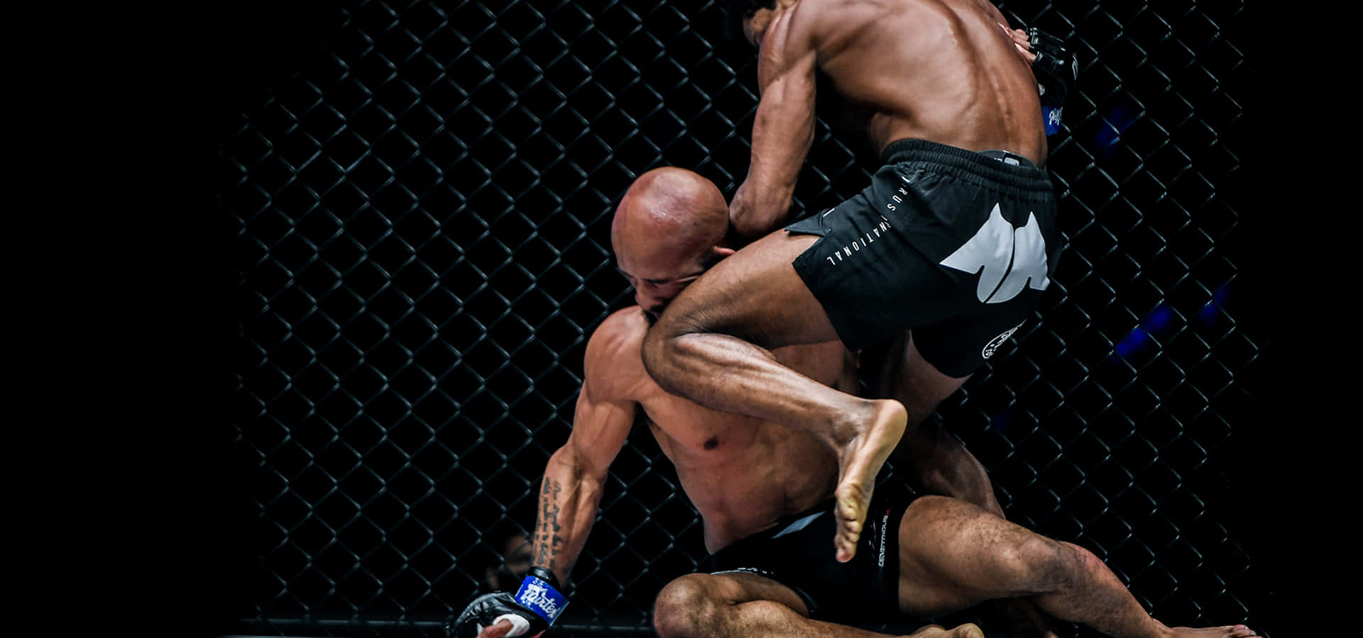 MMA 桌布 壁紙 — 兩位肌肉發達的拳手在昏暗的八角籠內激烈纏鬥，進行一場高風險的MMA比賽。