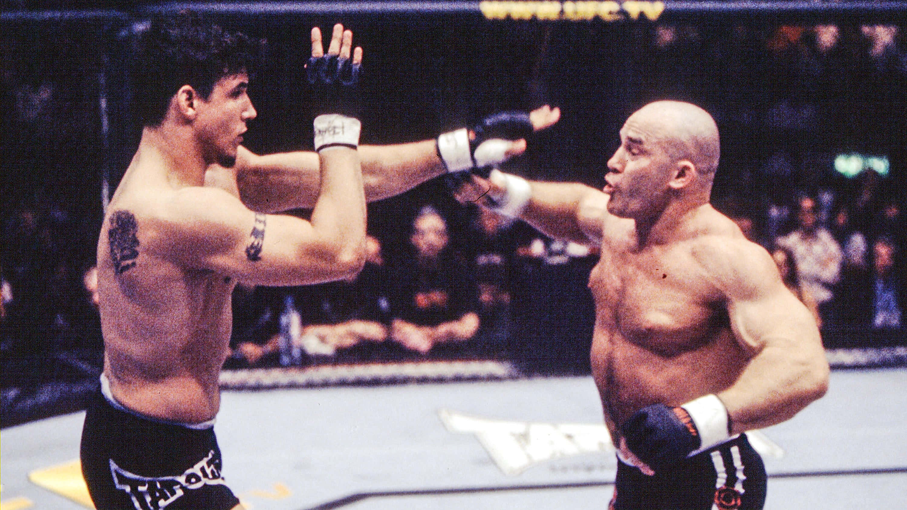 UFC 桌布 壁紙 — 兩位肌肉發達的拳手在燈光明亮的MMA八角籠內緊張時刻交換手套。