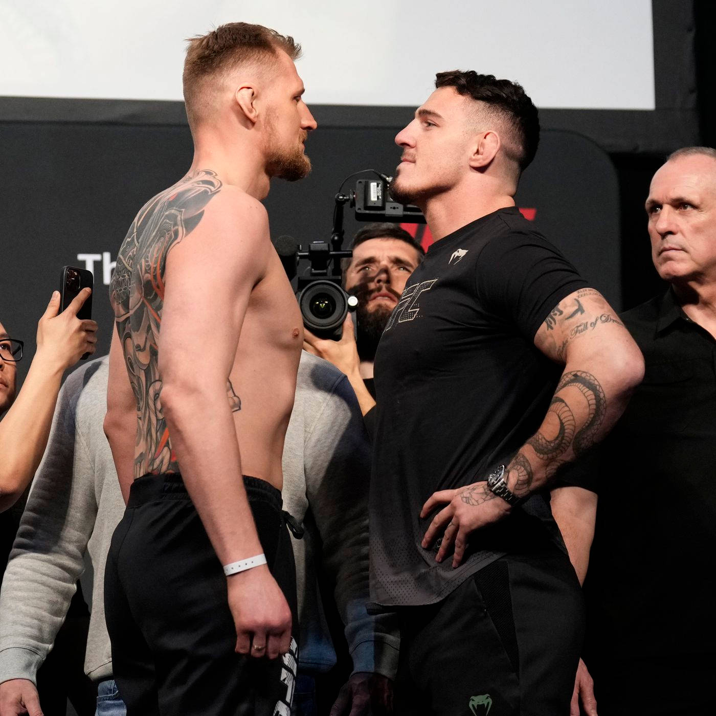 UFC 桌布 壁紙 — 兩位肌肉發達的拳手在磅重時激烈對峙，周圍閃光燈不斷。