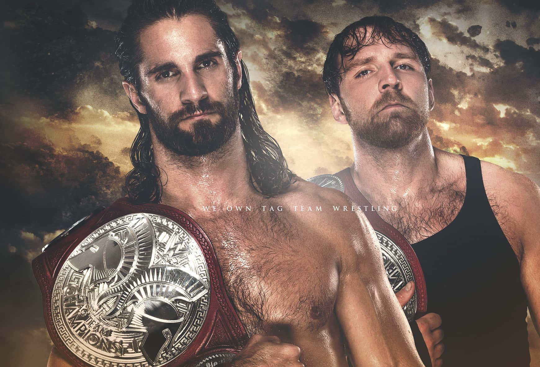 WWE 桌布 壁紙 — 兩位肌肉發達的摔角手帶著冠軍腰帶，站在暴風雨般戲劇性的天空下，天空閃耀著夕陽的色彩。