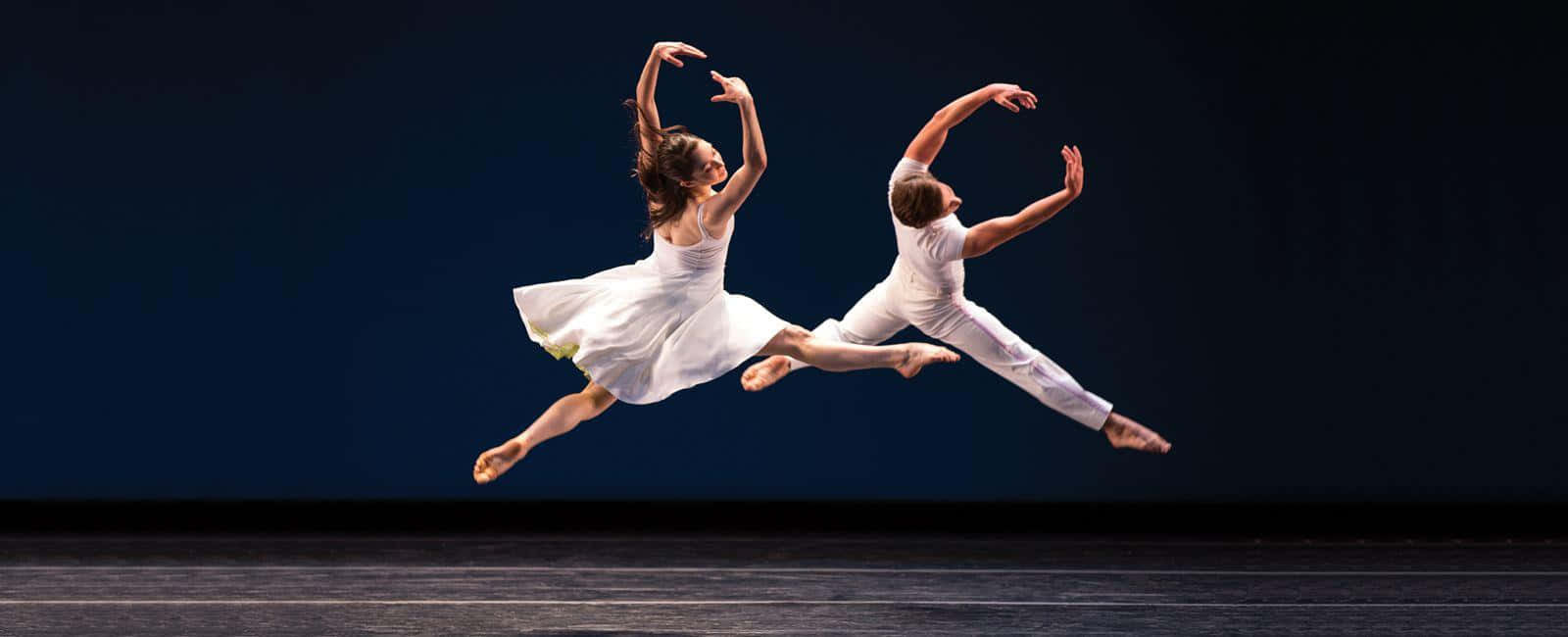 Ballet 桌布 壁紙 — 兩位芭蕾舞者在深藍色舞台背景下同步優雅躍起。