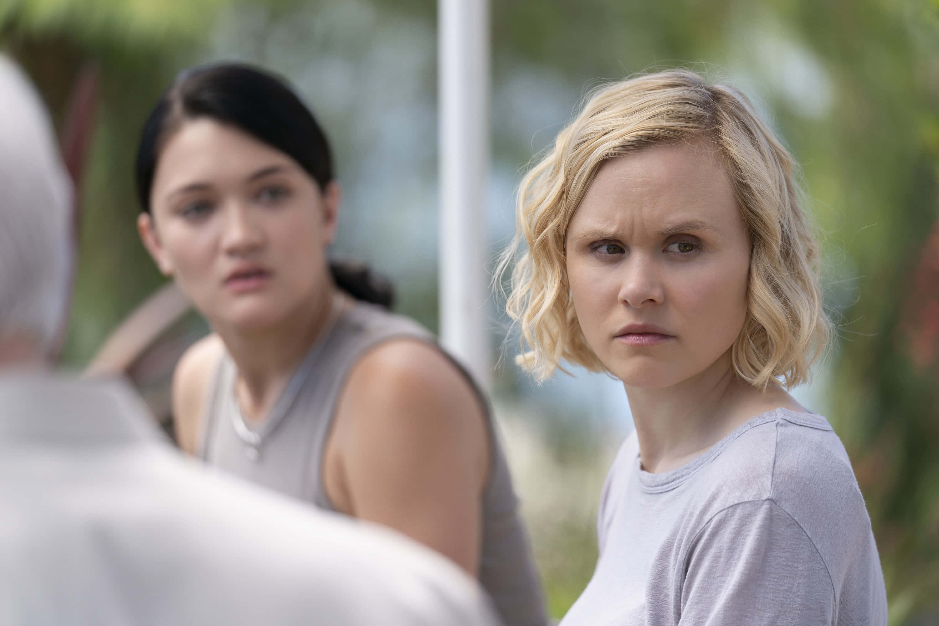 Alison Pill 桌布 壁紙 — 兩位表情緊張的女性坐在戶外，一位金髮皺眉，另一位黑髮看起來很擔心。
