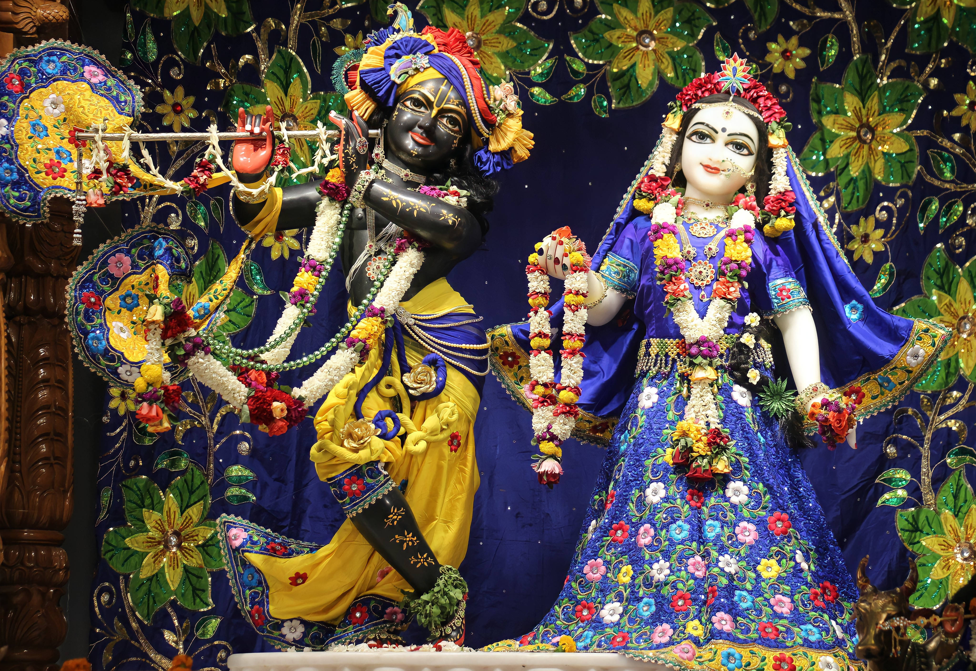 krishna 3d 桌布 壁紙 — 兩位裝飾華麗的印度教神祇克里希納和拉妲，優雅地站在繡花豐富的花卉背景前。