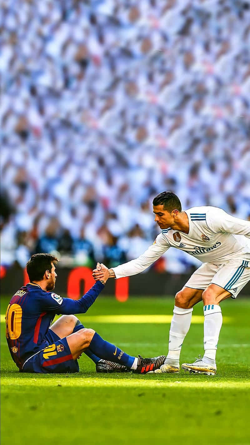 Messi And Ronaldo 4K 桌布 壁紙 — 兩位足球傳奇人物在充滿活力的綠色球場上，在咆哮的體育場人群面前握手。