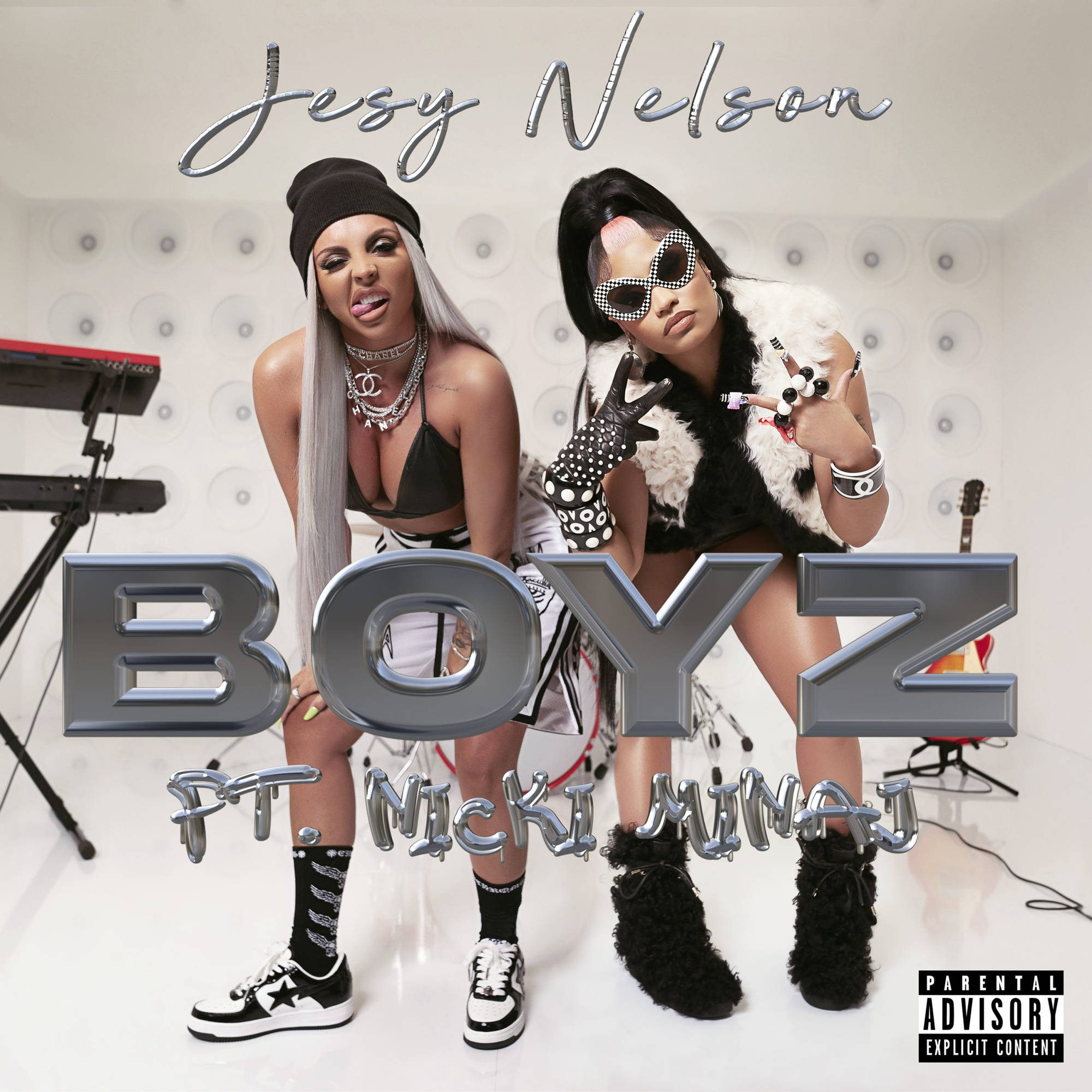 Jesy Nelson 桌布 壁紙 — 兩位身穿大膽黑白服裝的女性在簡約的工作室中自信地擺姿勢，周圍有樂器和金屬質感的專輯文字。