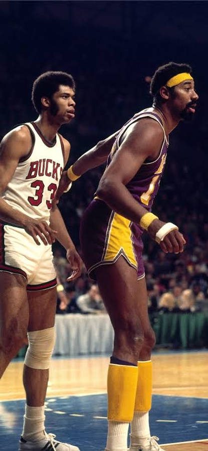 NBA 桌布 壁紙 — 兩位身穿復古球衣的NBA籃球運動員在場館燈光下的硬木球場上激烈比賽。