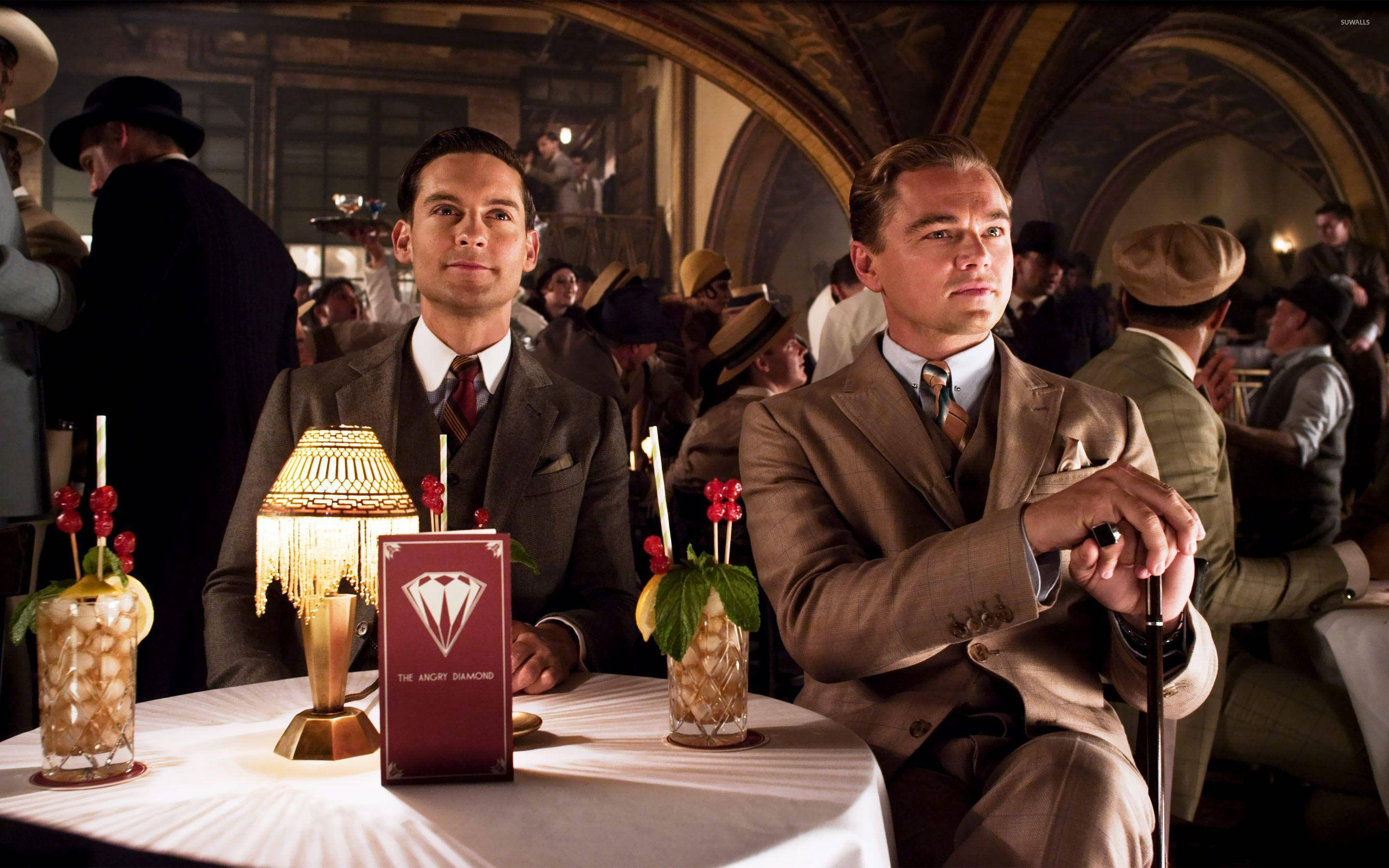Wolf Of Wall Street 桌布 壁紙 — 兩位身穿復古西裝的男子坐在燈光昏暗的非法酒吧桌旁，桌上放著雞尾酒和一盞發光的燈。
