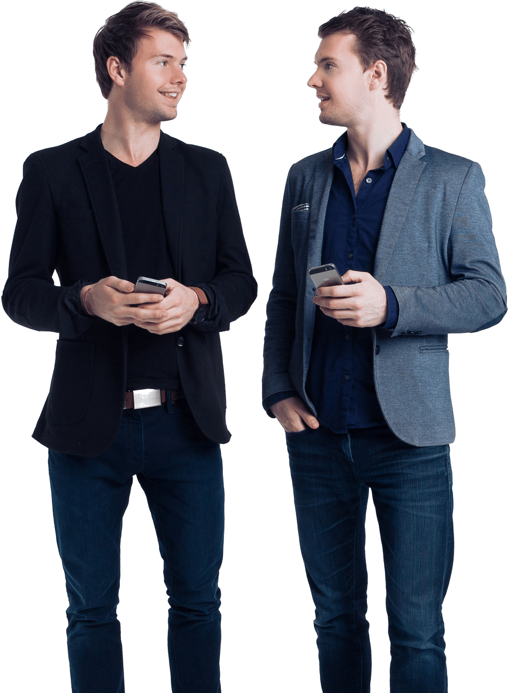 twins 桌布 壁紙 — 兩位身穿時尚休閒裝的男士站在黑色背景前，手持智慧型手機，微笑著互相對望。
