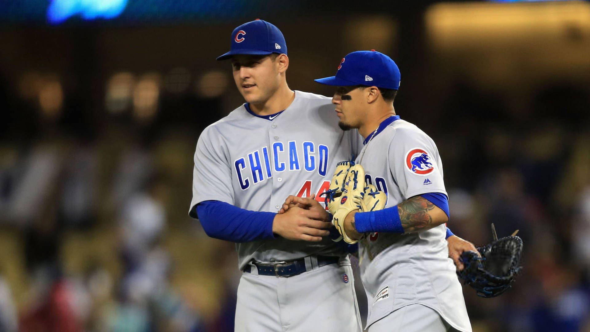 Cubs 桌布 壁紙 — 兩位身穿灰色球衣的芝加哥小熊隊棒球選手在球場燈光下於球場上溫暖擁抱。