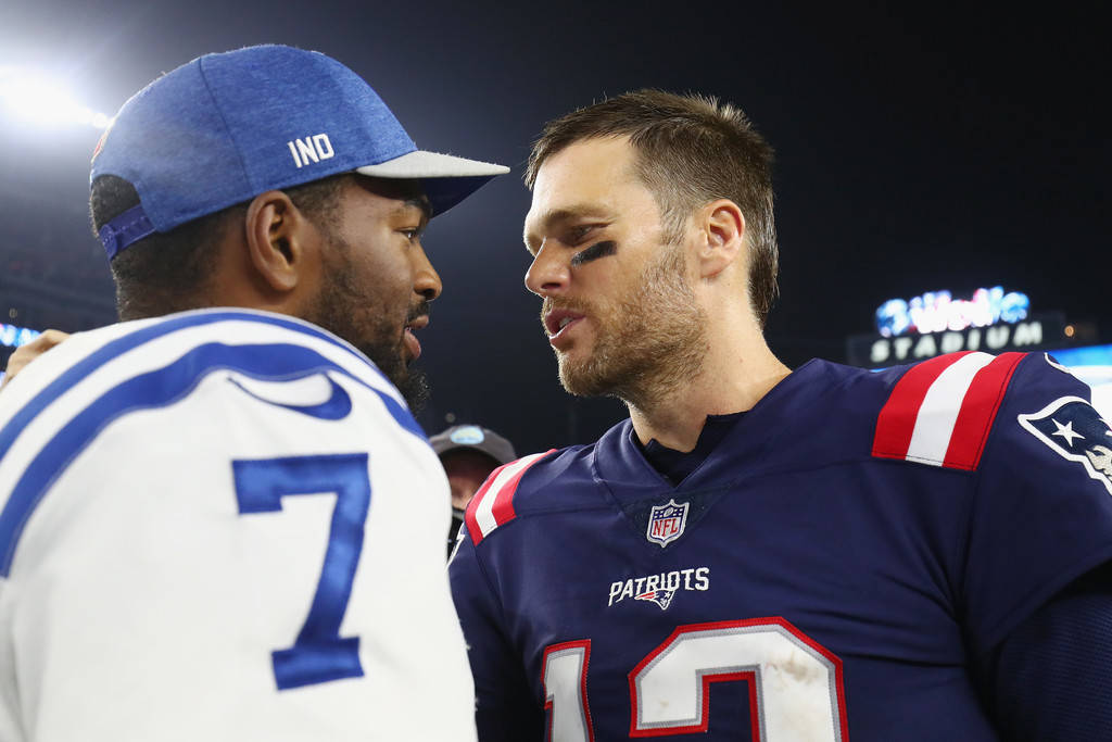 桌布 壁紙 — 兩位身穿球隊球衣的NFL四分衛在比賽期間於明亮燈光下的體育館內面對面。