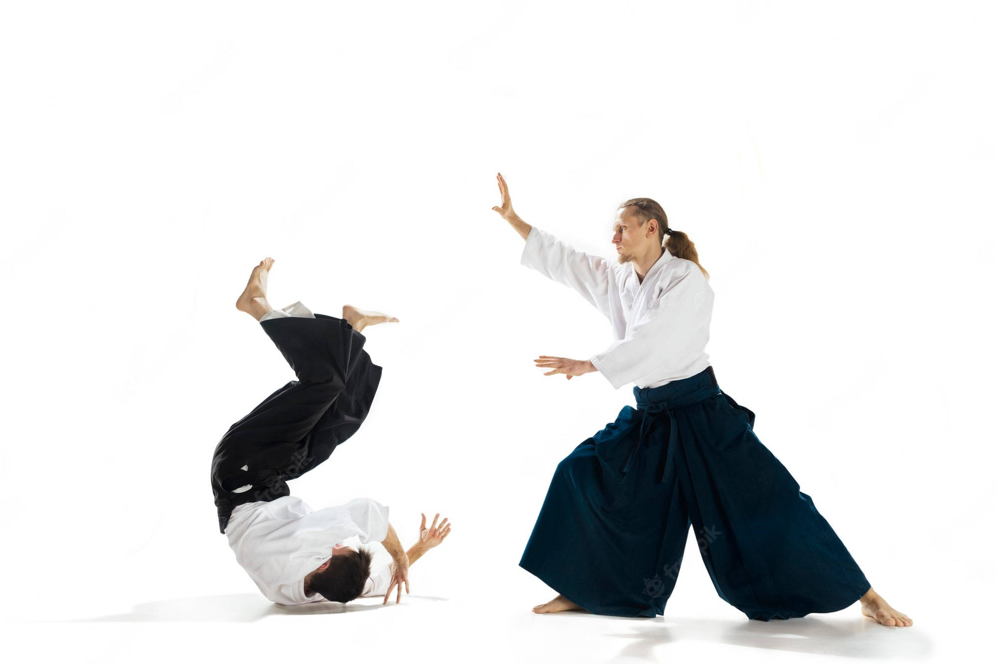 martial arts 桌布 壁紙 — 兩位身穿白色和深藍色道服的武術家，在純白的工作室背景下展示動態的合氣道技巧。