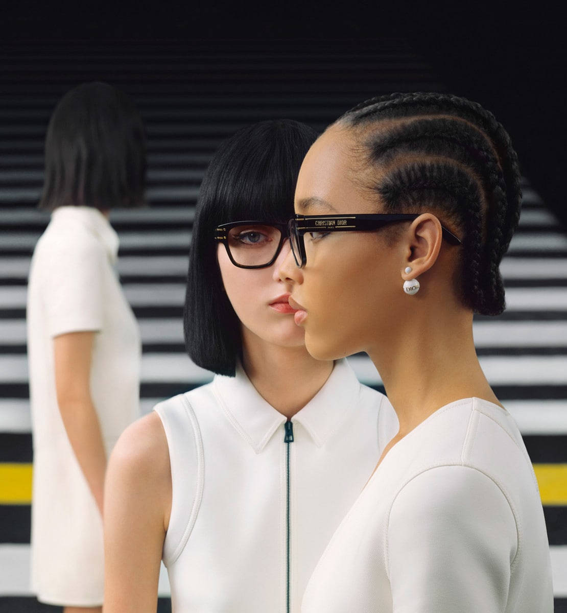 兩位時尚女性身穿白色服裝、戴著眼鏡，站在條紋背景前。 — Dior 動態 壁紙