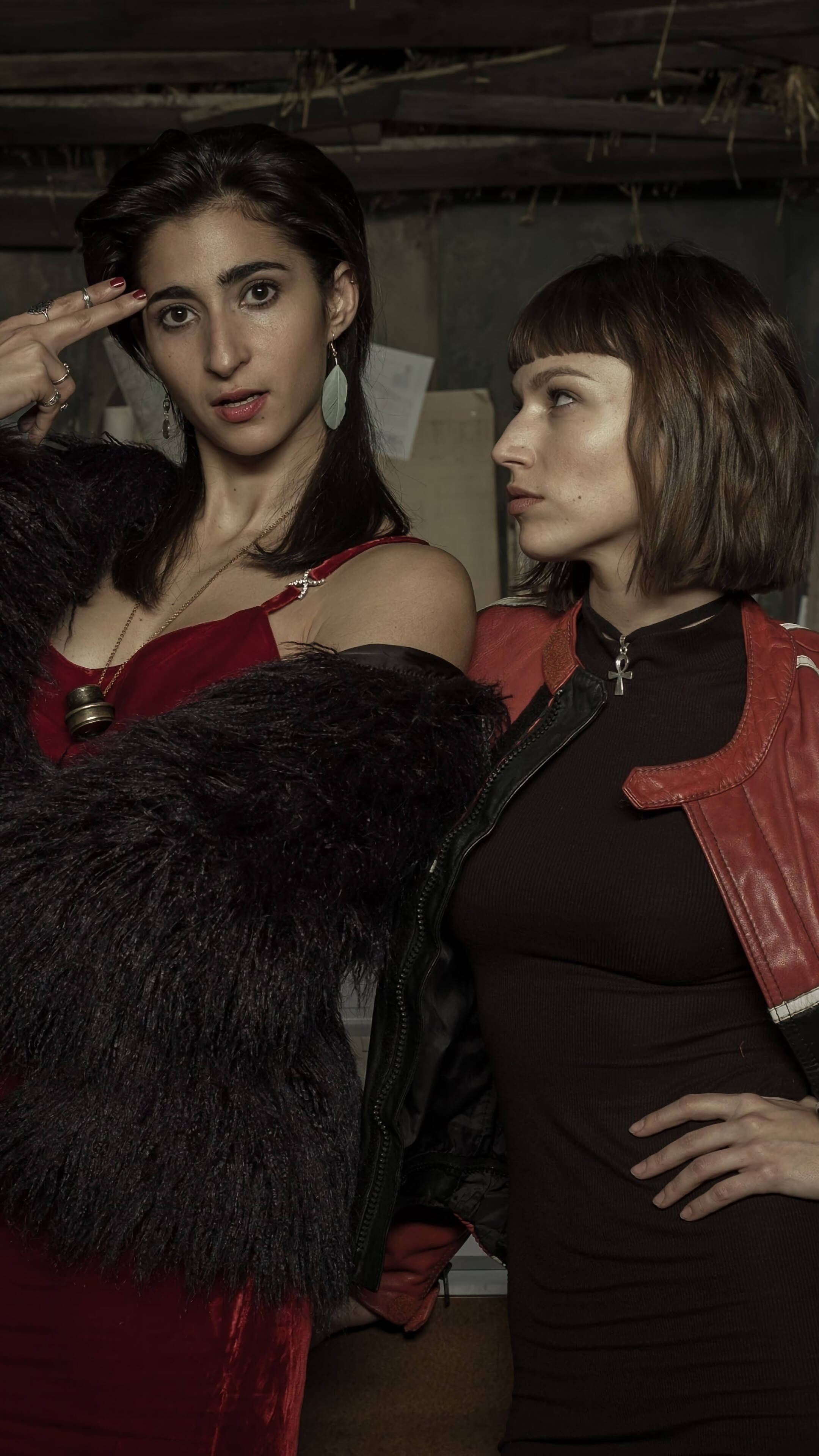 nairobi money heist 桌布 壁紙 — 兩位身穿紅色服裝的女性在光線昏暗的地下室中，以裸露的橫樑和乾草為背景，戲劇性地擺姿勢。
