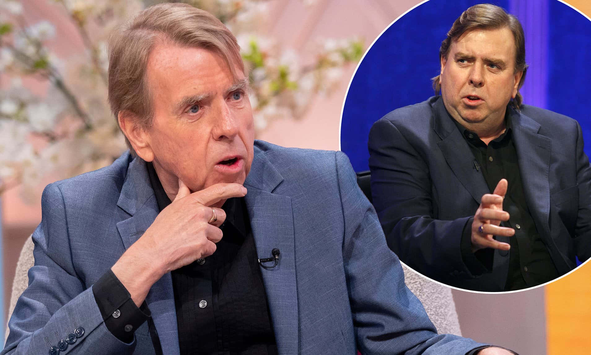 Timothy Spall 桌布 壁紙 — 兩位身穿西裝的男士在設有花卉背景的脫口秀舞台上進行嚴肅對話。