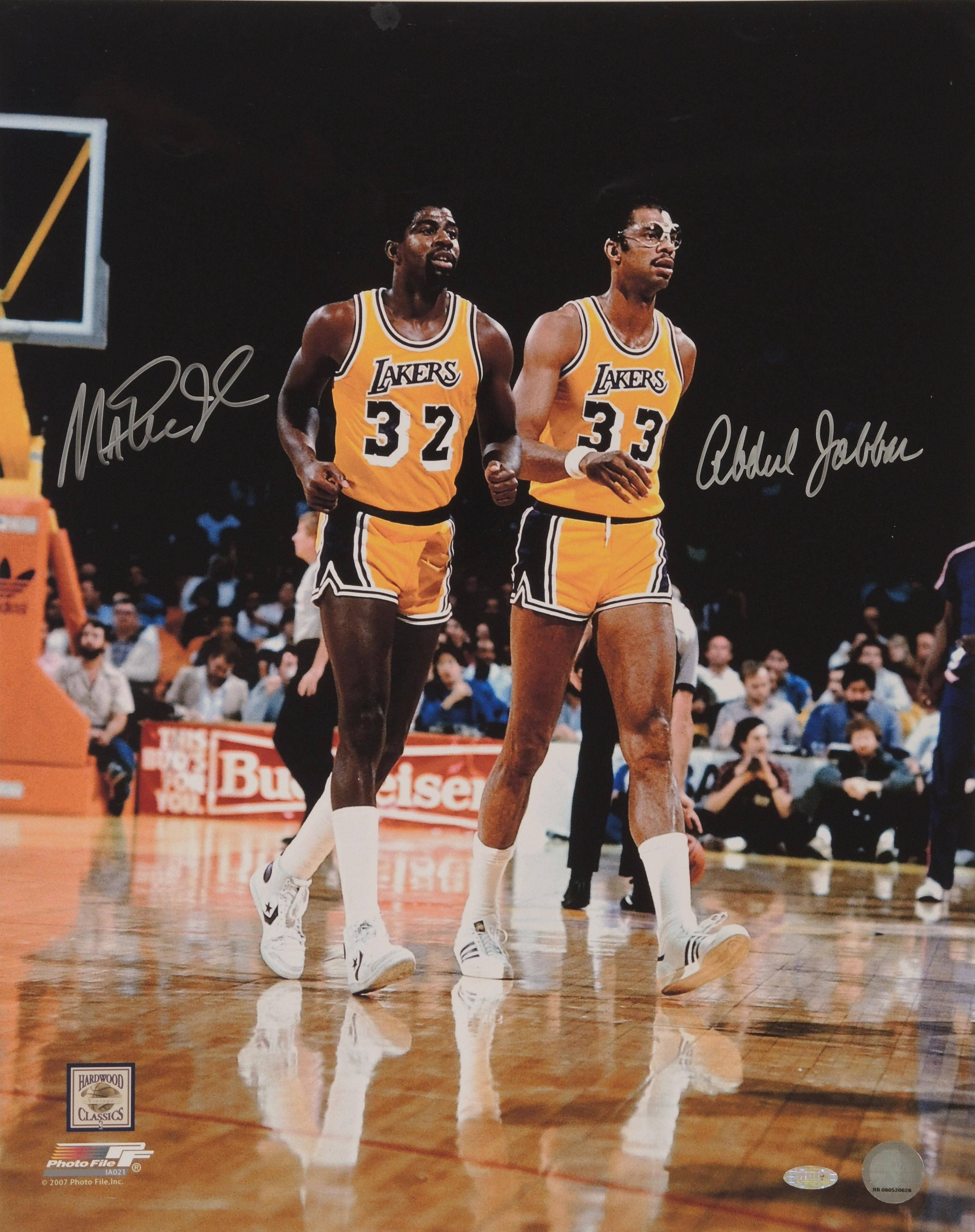 Kareem 桌布 壁紙 — 兩位身穿黃色球衣的標誌性湖人籃球運動員在體育館燈光下並肩走在拋光球場上。