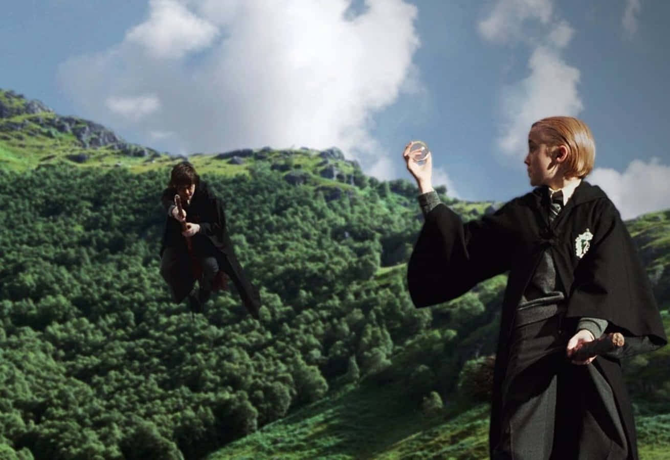 The Hogwarts Flying Lessons 桌布 壁紙 — 兩位身穿黑色長袍的巫師在晴朗藍天和蓬鬆白雲下，飛越一片翠綠茂密的森林山坡。