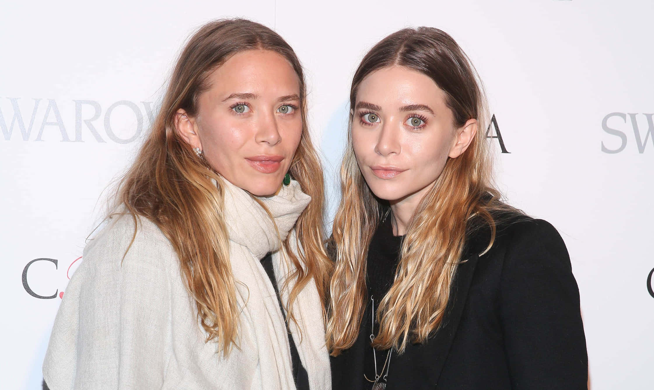 ashley olsen 桌布 壁紙 — 兩位長金髮女性在活動中緊貼白色品牌背景擺姿勢。