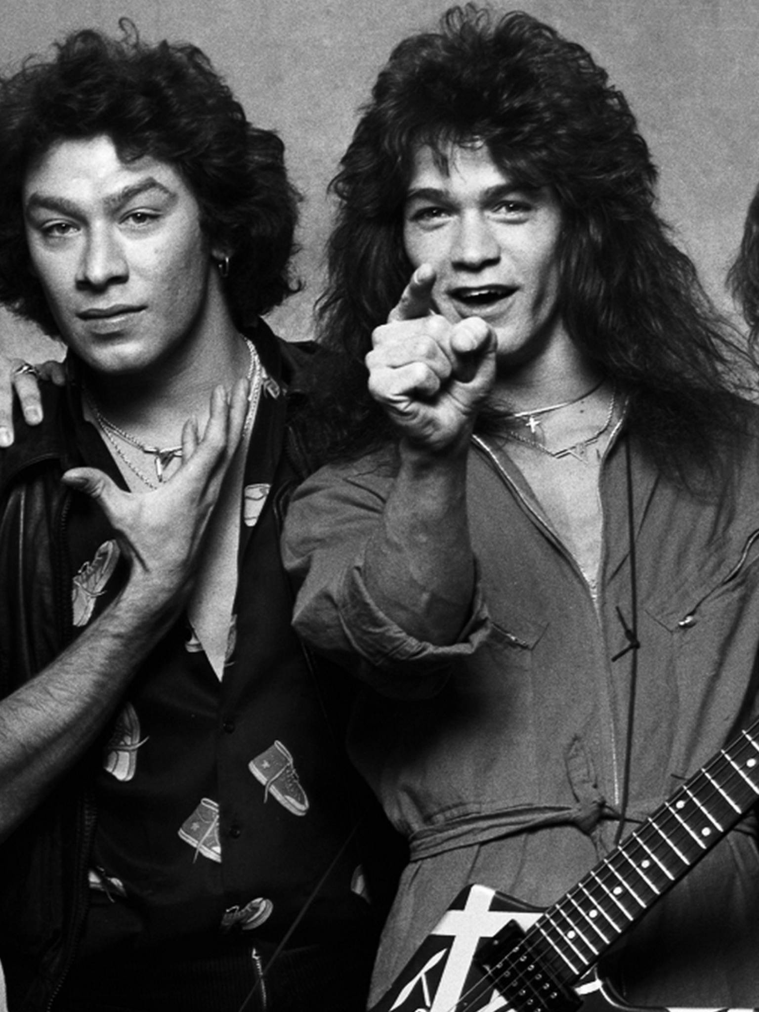 80s Rock 桌布 壁紙 — 兩位長髮搖滾音樂家在經典黑白工作室照中激烈擺姿勢，其中一人指向前方並手持吉他。