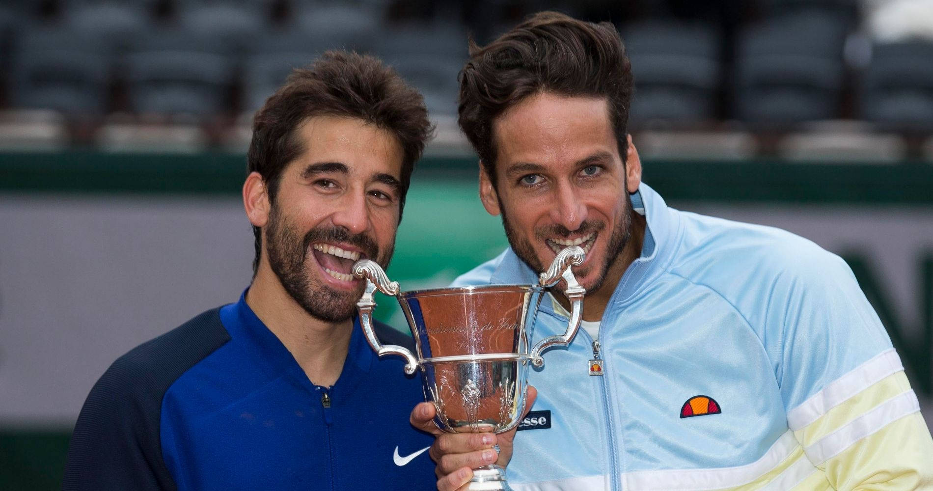 Tennis 桌布 壁紙 — 兩位開心的網球運動員在紅土球場上分享閃亮的銀色獎盃，咧嘴大笑。
