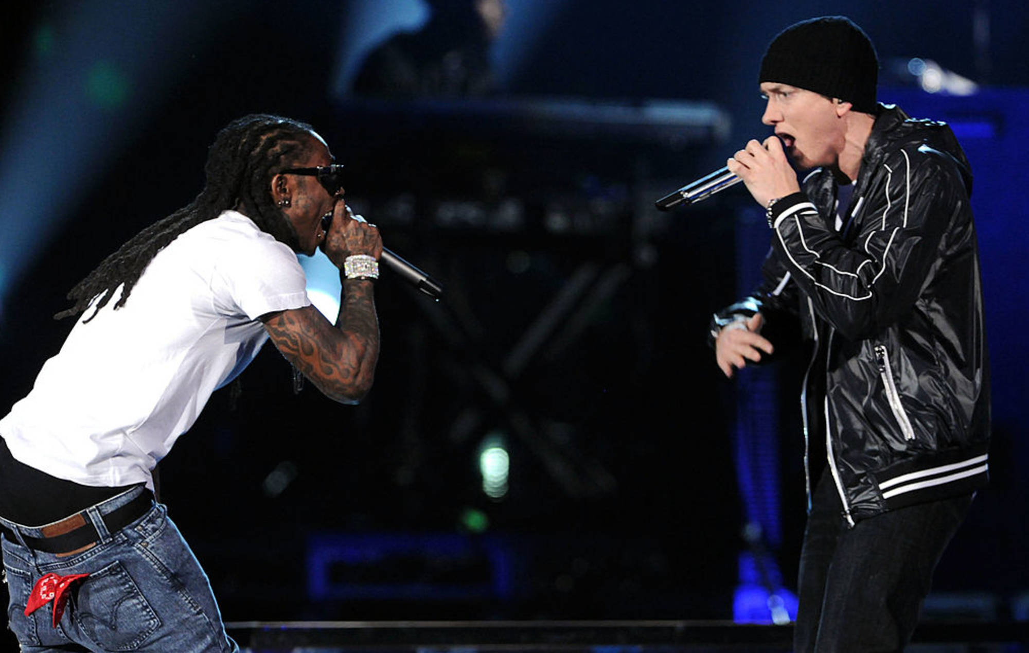 Lil Wayne 桌布 壁紙 — 兩位饒舌歌手在燈光昏暗的舞台上，手持藍色聚光燈和麥克風，進行激烈的表演。