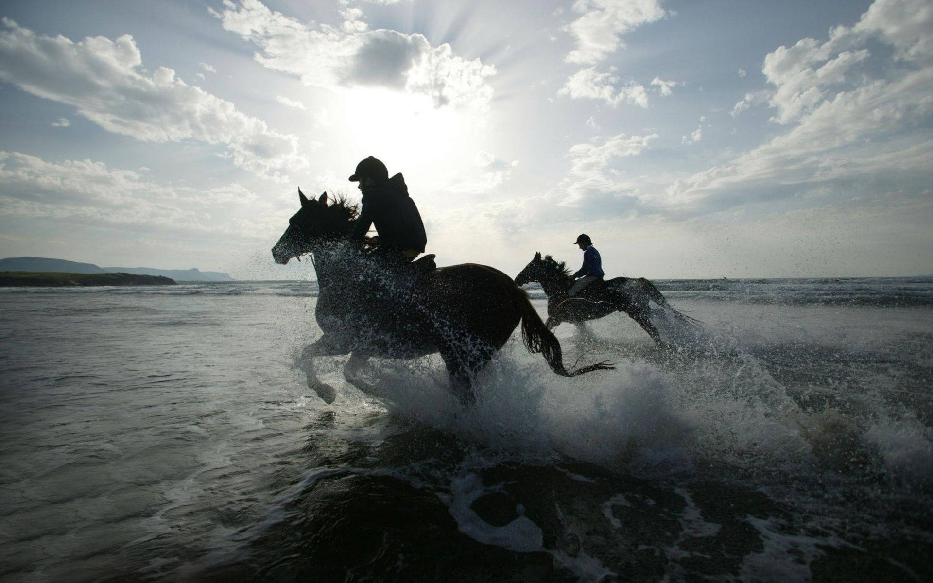 Horse Racing 桌布 壁紙 — 兩位騎手騎著奔騰的馬匹，在明亮的陽光下衝過淺海海水，激起水花。