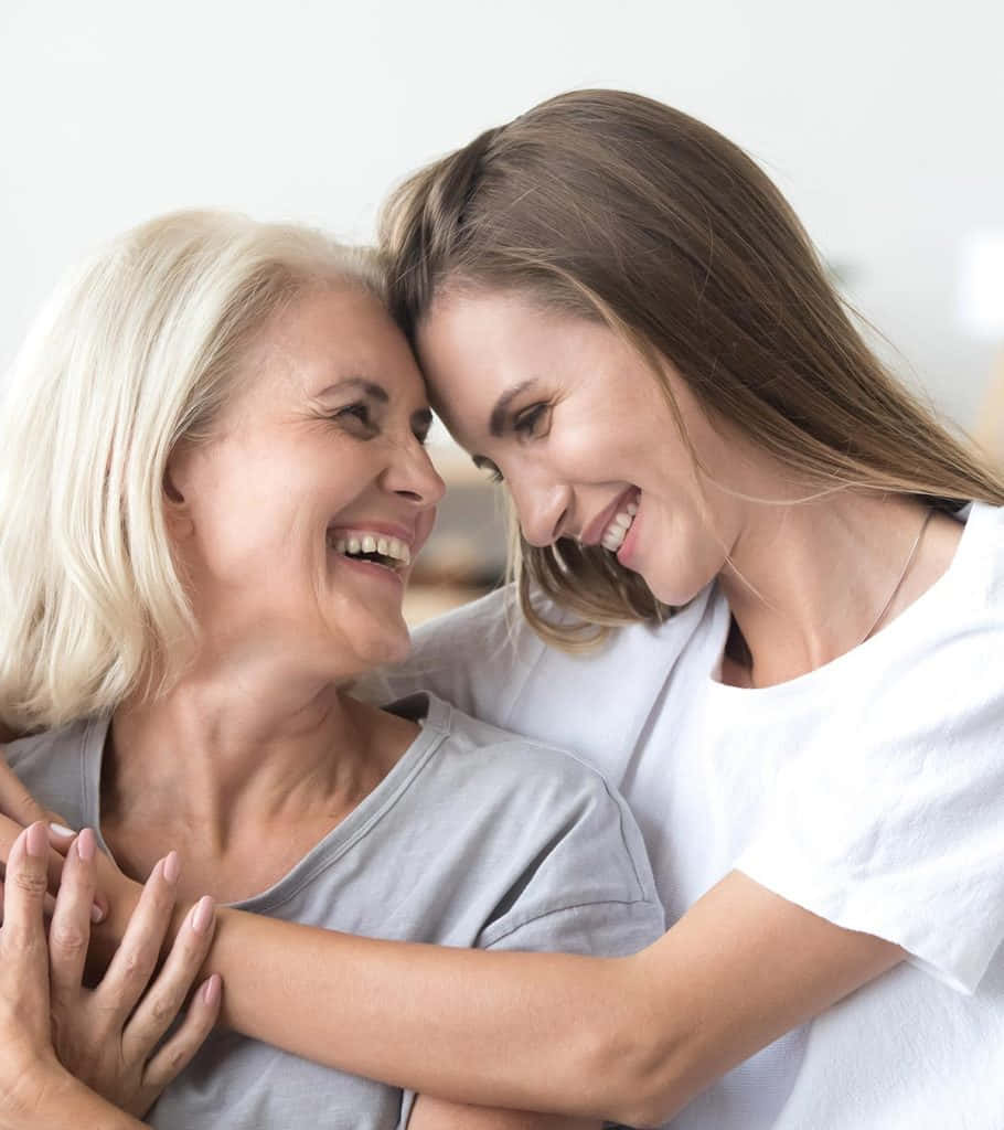Mother Love 桌布 壁紙 — 兩位髮色對比的女性分享一個快樂的擁抱，額頭相觸，在溫柔的聯繫時刻中。